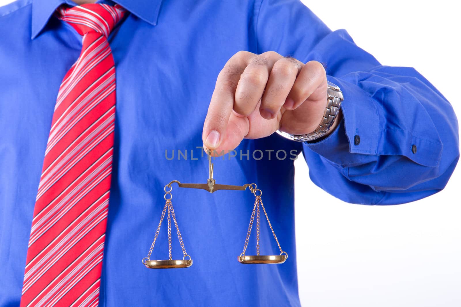 Businessman with red tie and blue shirt holding golden scales on balance, isolated on white background.