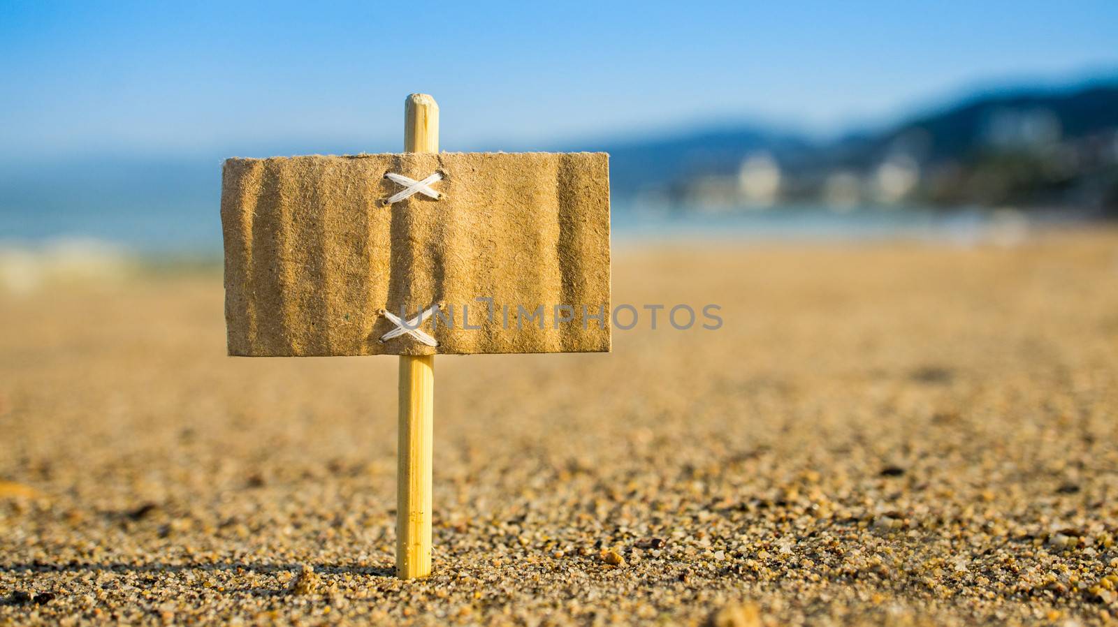 A miniature for sale sign on a tropical beach