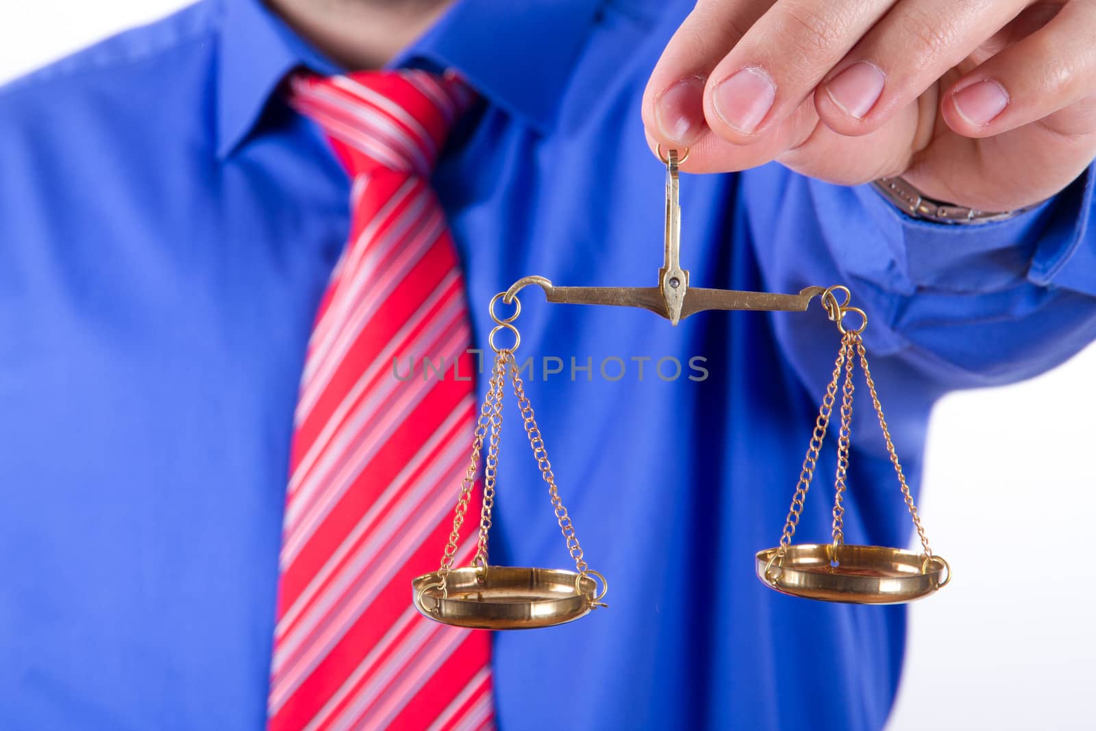 Businessman with red tie and blue shirt holding golden scales on balance, isolated on white background.
