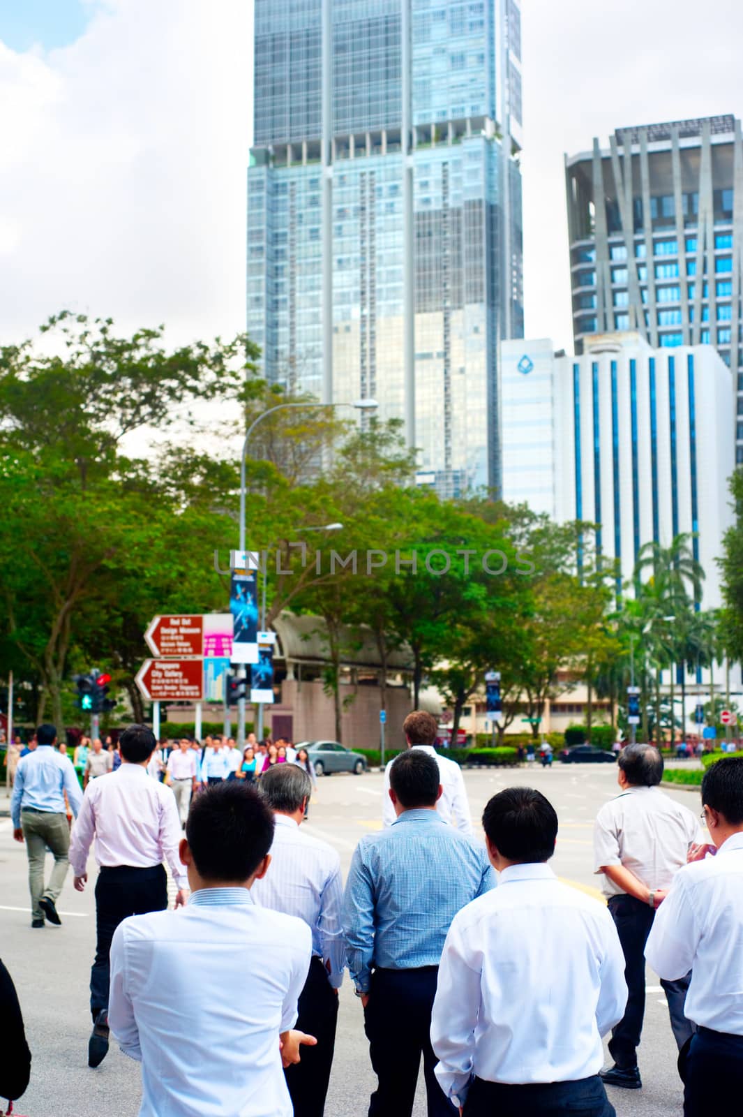 Singapore, Republic of Singapore - March 07, 2013: Unidentified businessmen crossing the street in Singapore. There are more than 7,000 multinational corporations from United States, Japan and Europe in Singapore.