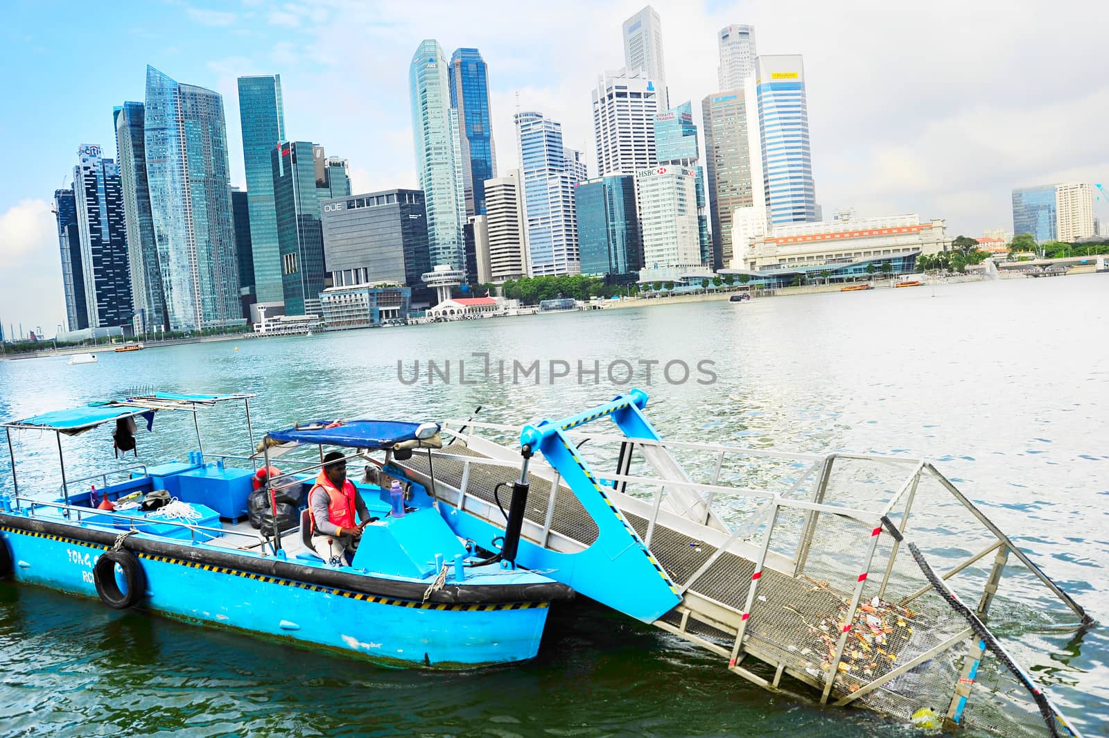 Singapore, Republic of Singapore - March 8, 2013: Water surface cleaning boat removing the garbage from the river in front of Singapore downtown