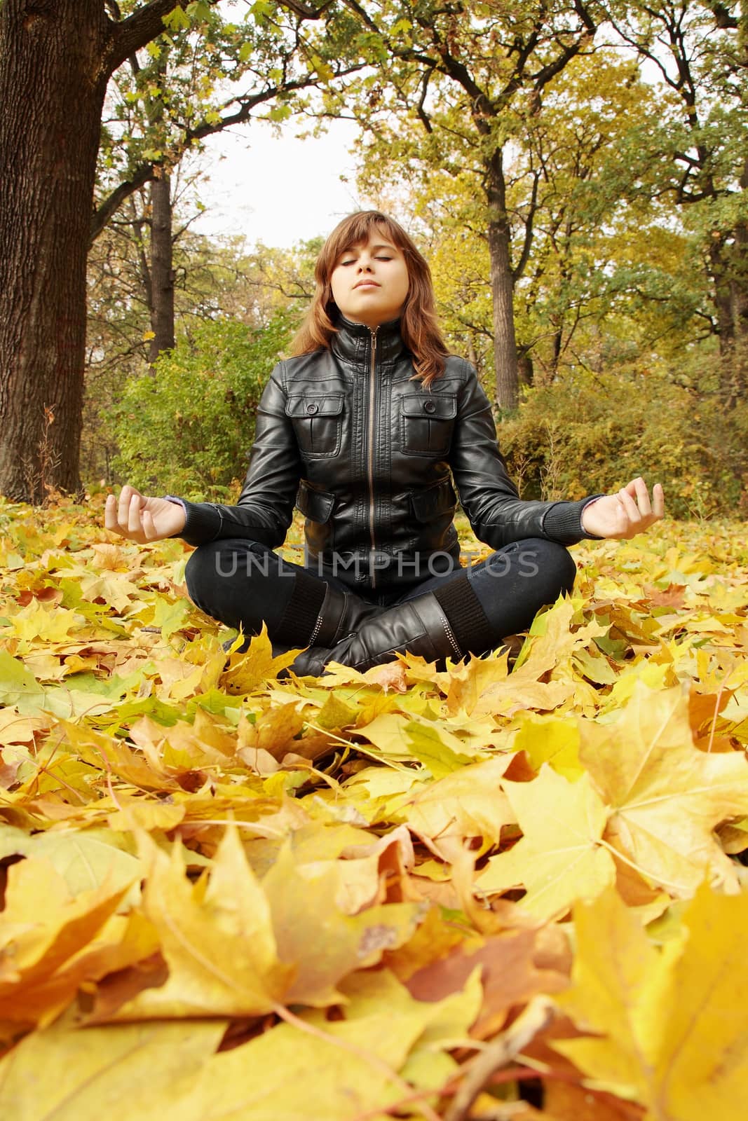 young woman meditates in the autumn park
