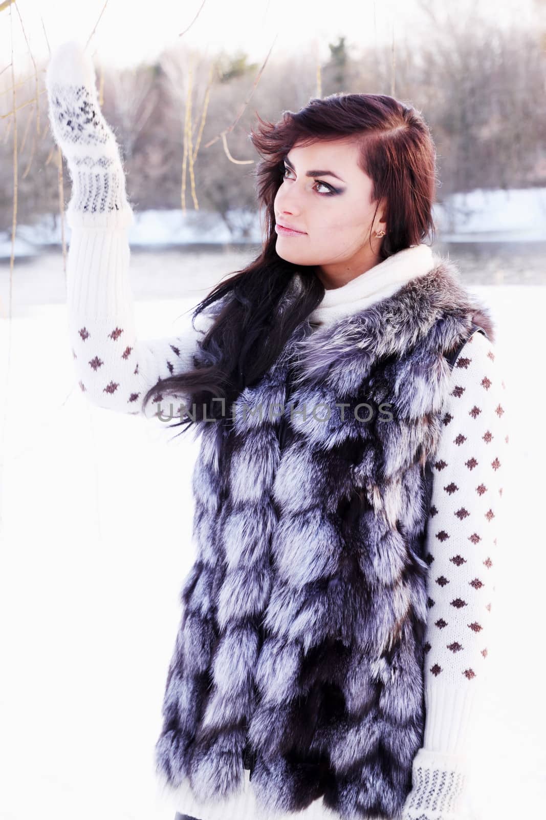 Young beautiful girl in a fur vest catches snow