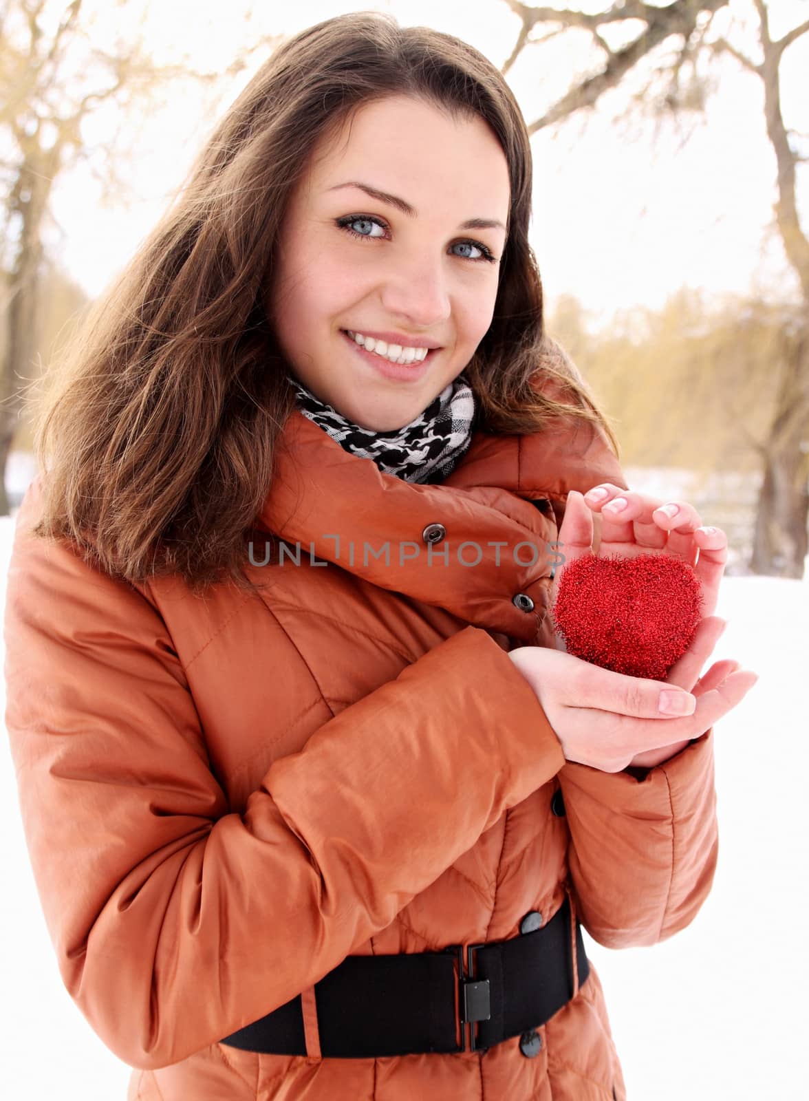 Young woman holding a red heart in the hands of