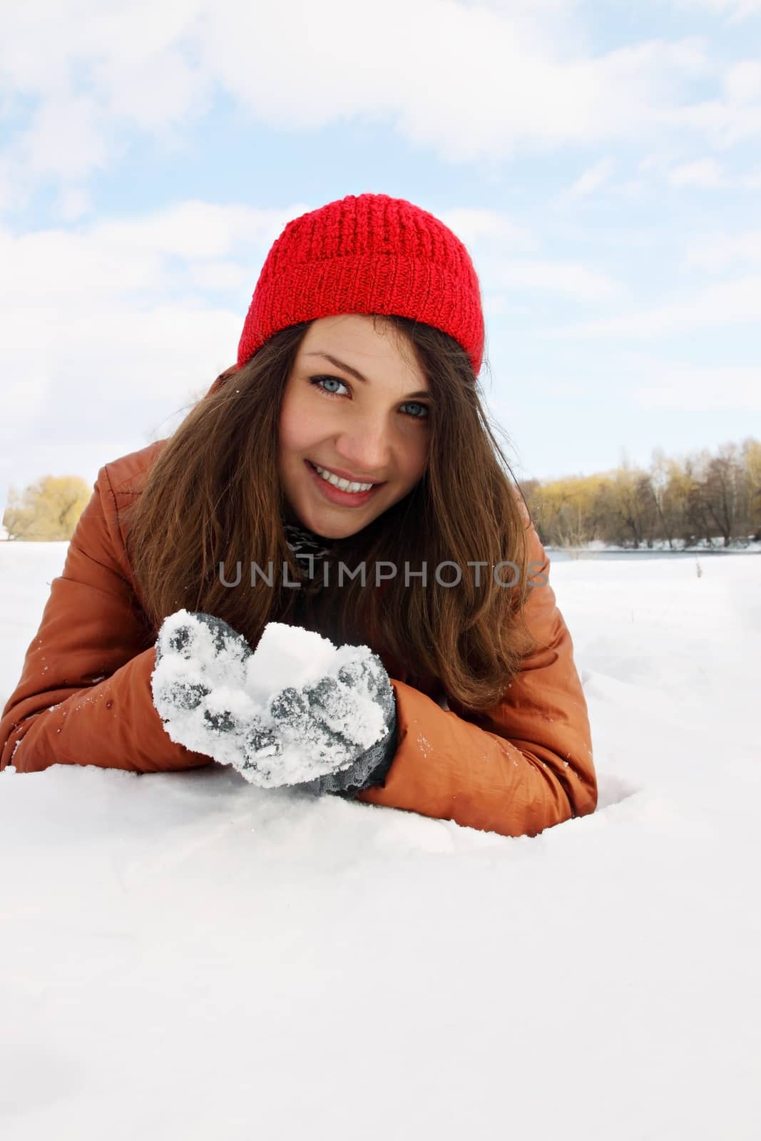 Woman lying in the snow and keeps the snow in their hands