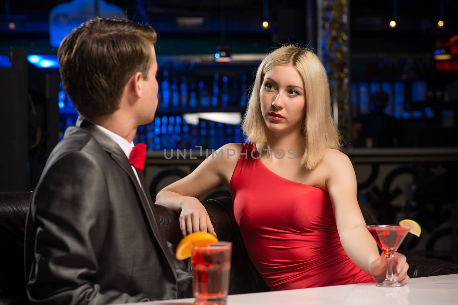 portrait of a woman in a nightclub, sitting on the couch and talking with man