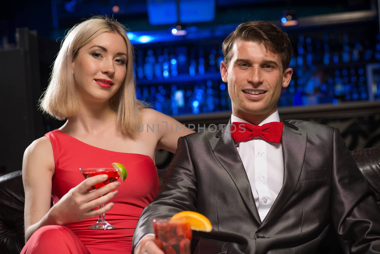 couple in a nightclub on the couch with a drink, have fun