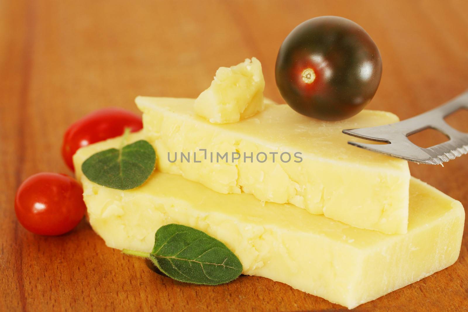 piece of cheese with small tomatoes on a wooden board