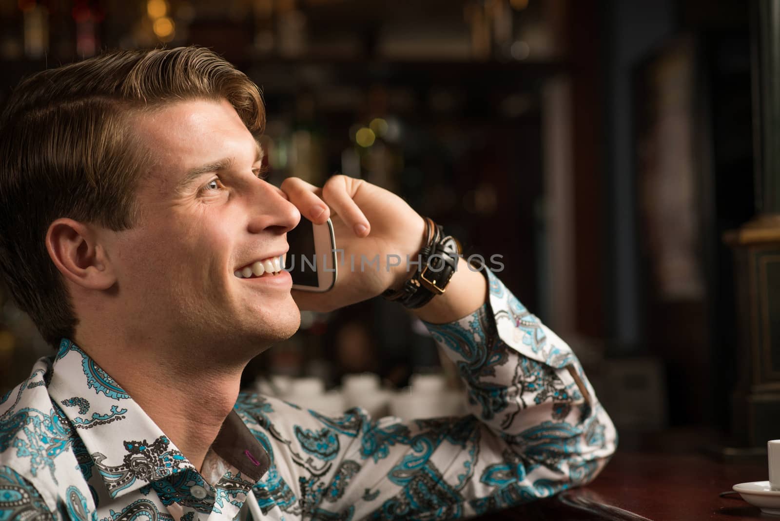 young man at the bar on the phone and drinking coffee