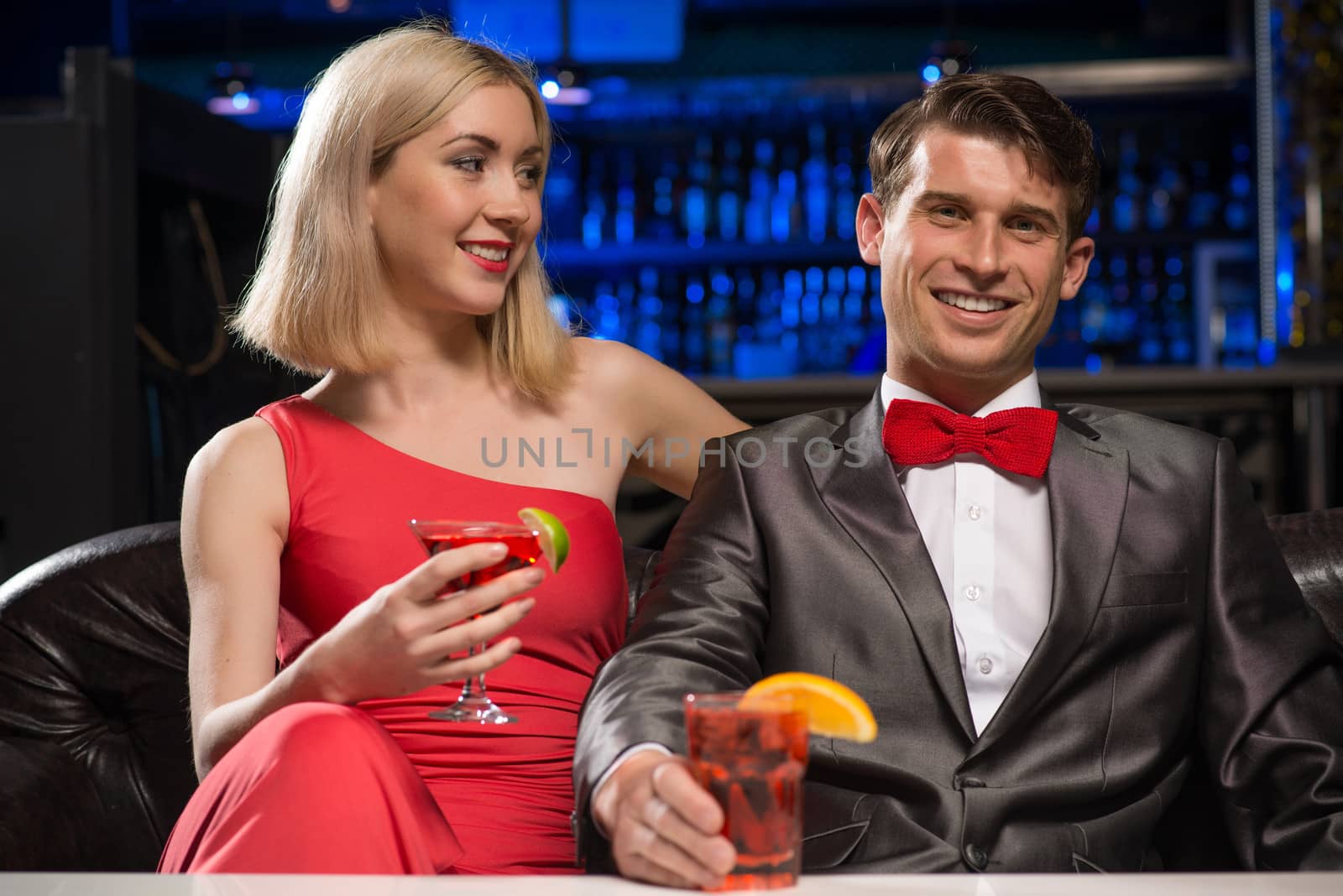 couple in a nightclub on the couch with a drink, have fun