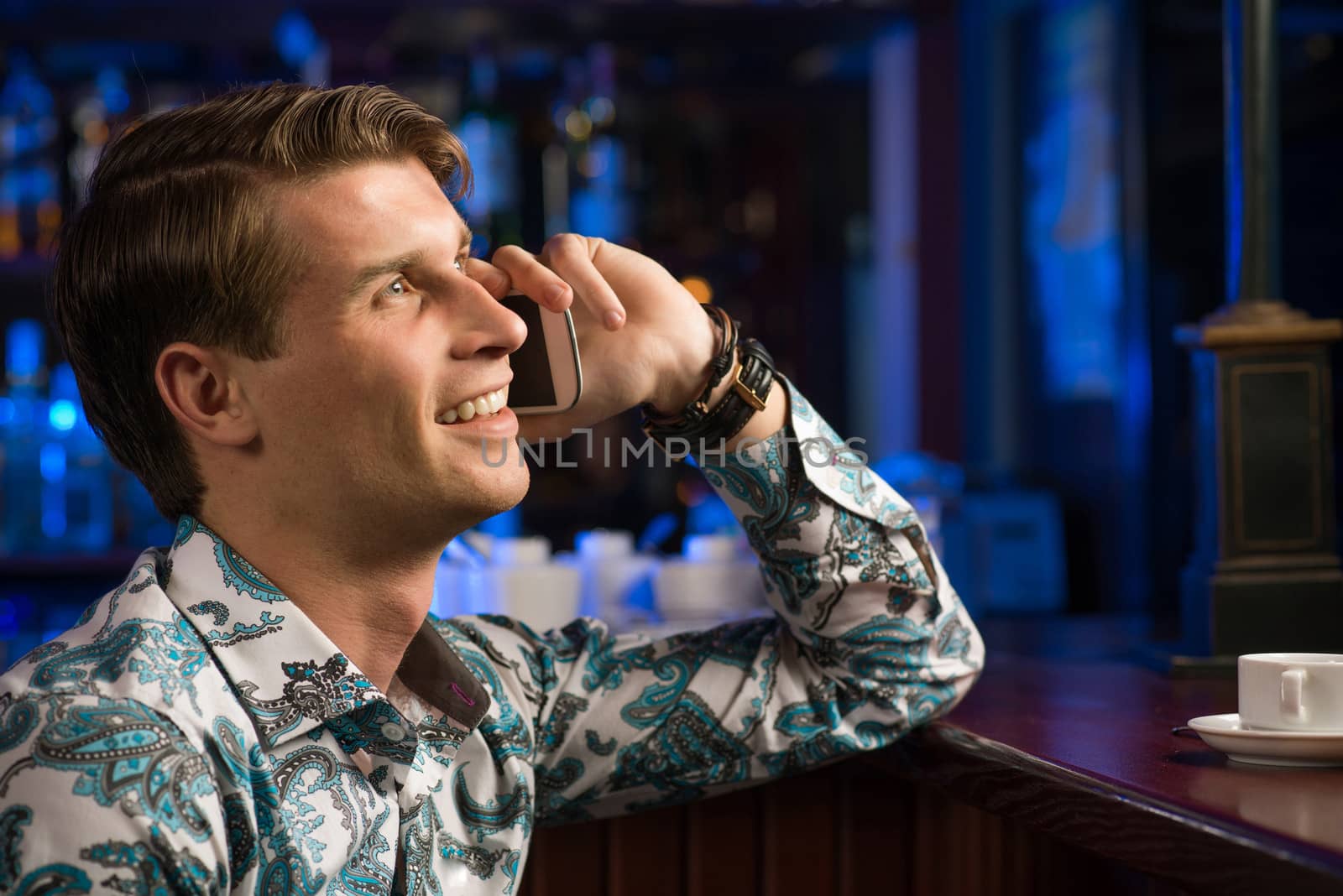 young man at the bar on the phone and drinking coffee