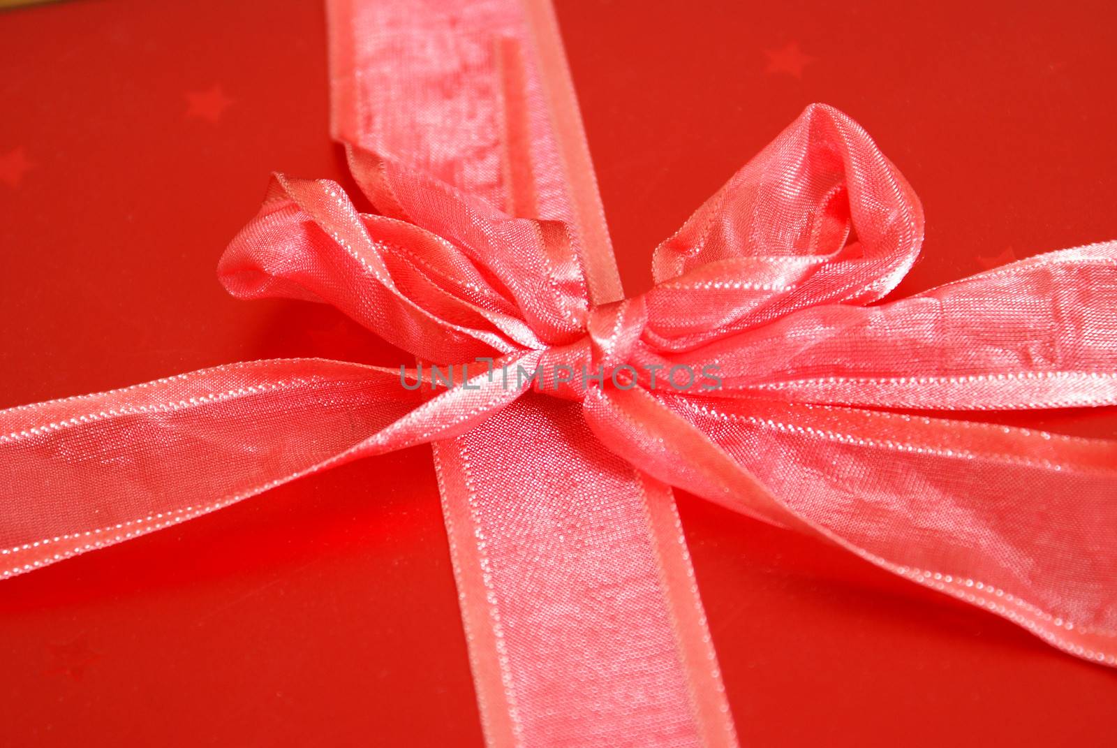 A macro shot of a red ribbon tied in a bow around a gift box.