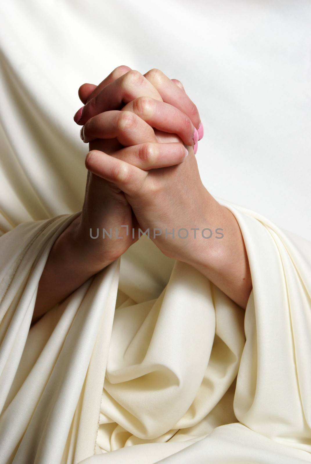 A young woman faithfully brings her hands together in essence of prayer.