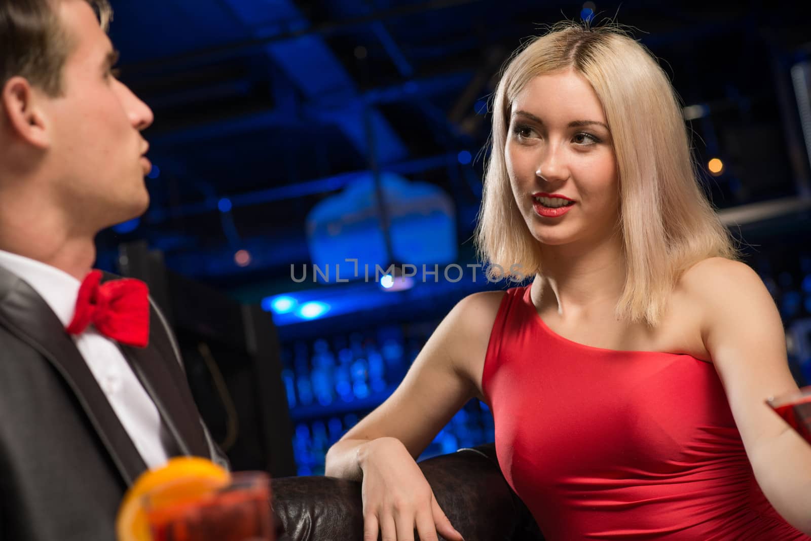 portrait of a woman in a nightclub, sitting on the couch and talking with man