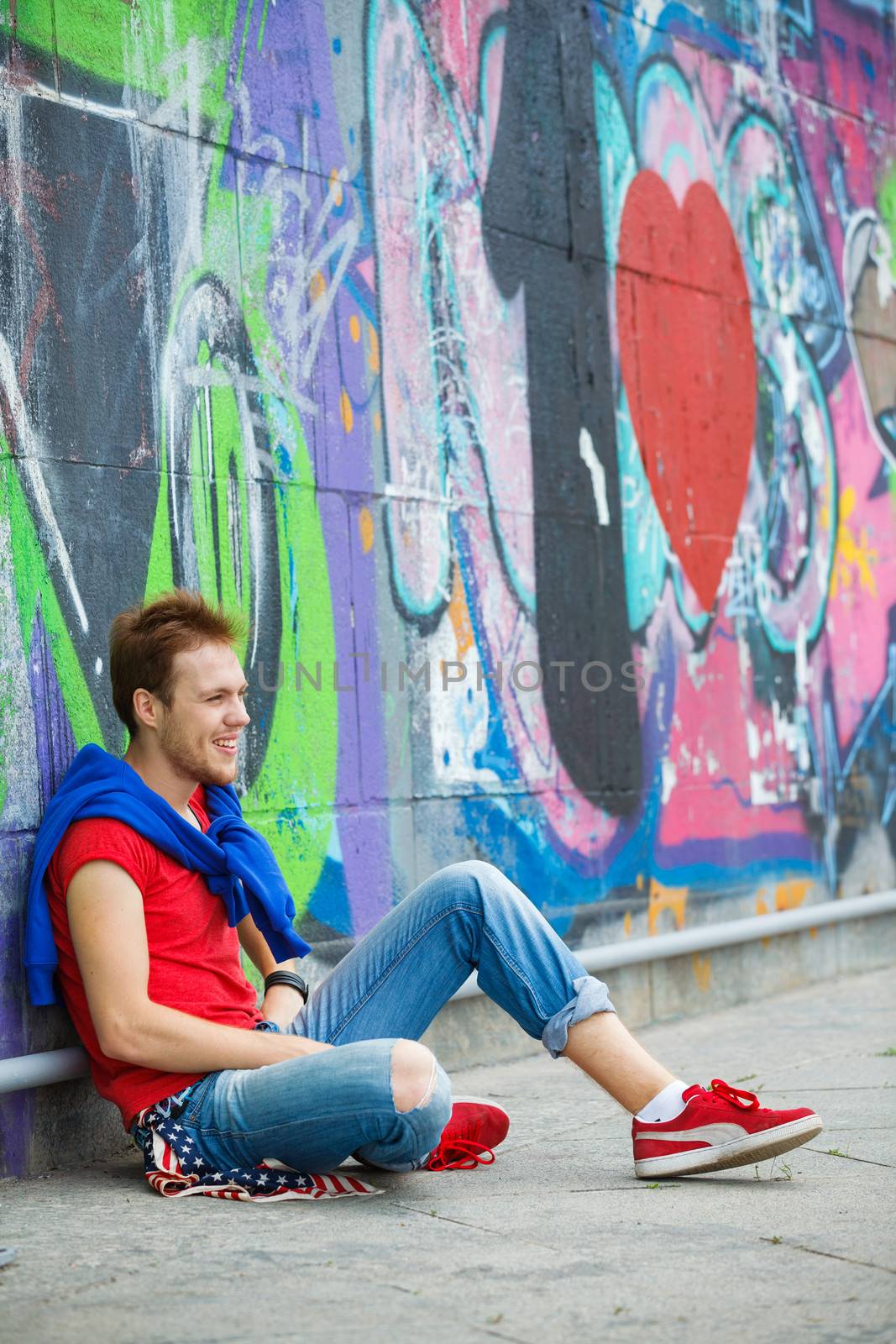 Happy teens boy sitting near painted wall and having fun