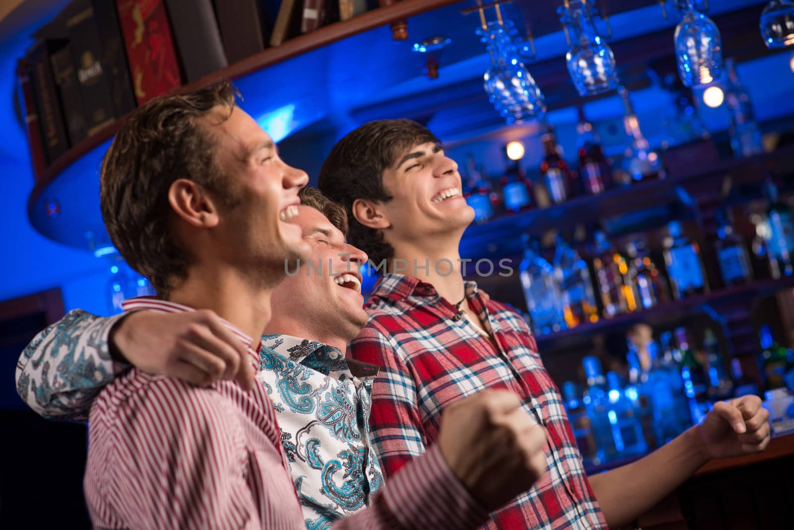 Three men stand in a row embracing smile and look in front of you, sports fans