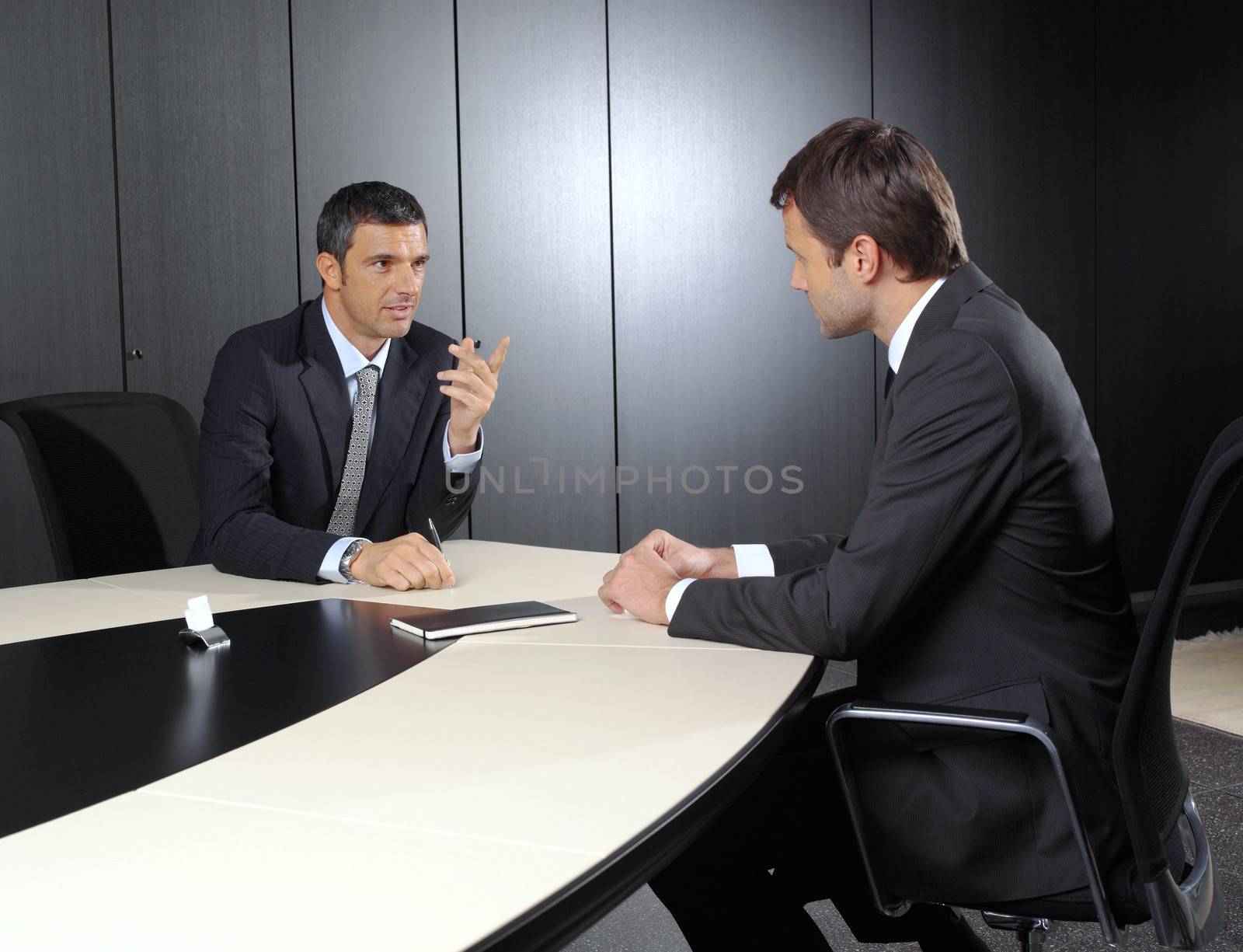 Two businessmen discussing tasks sitting at office table