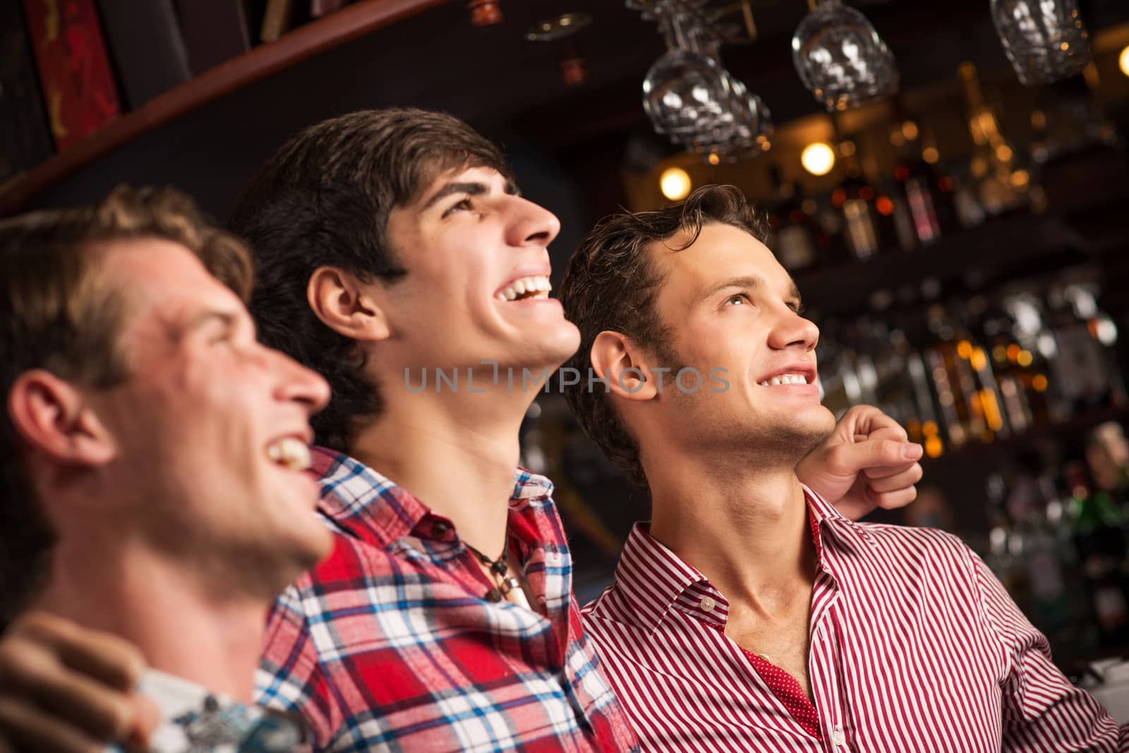 Three men stand in a row embracing smile and look in front of you, sports fans