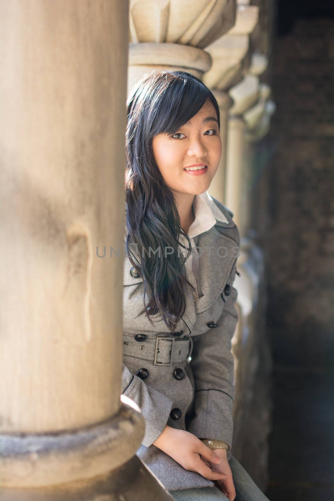 Young woman sitting next to a row of stone pillars