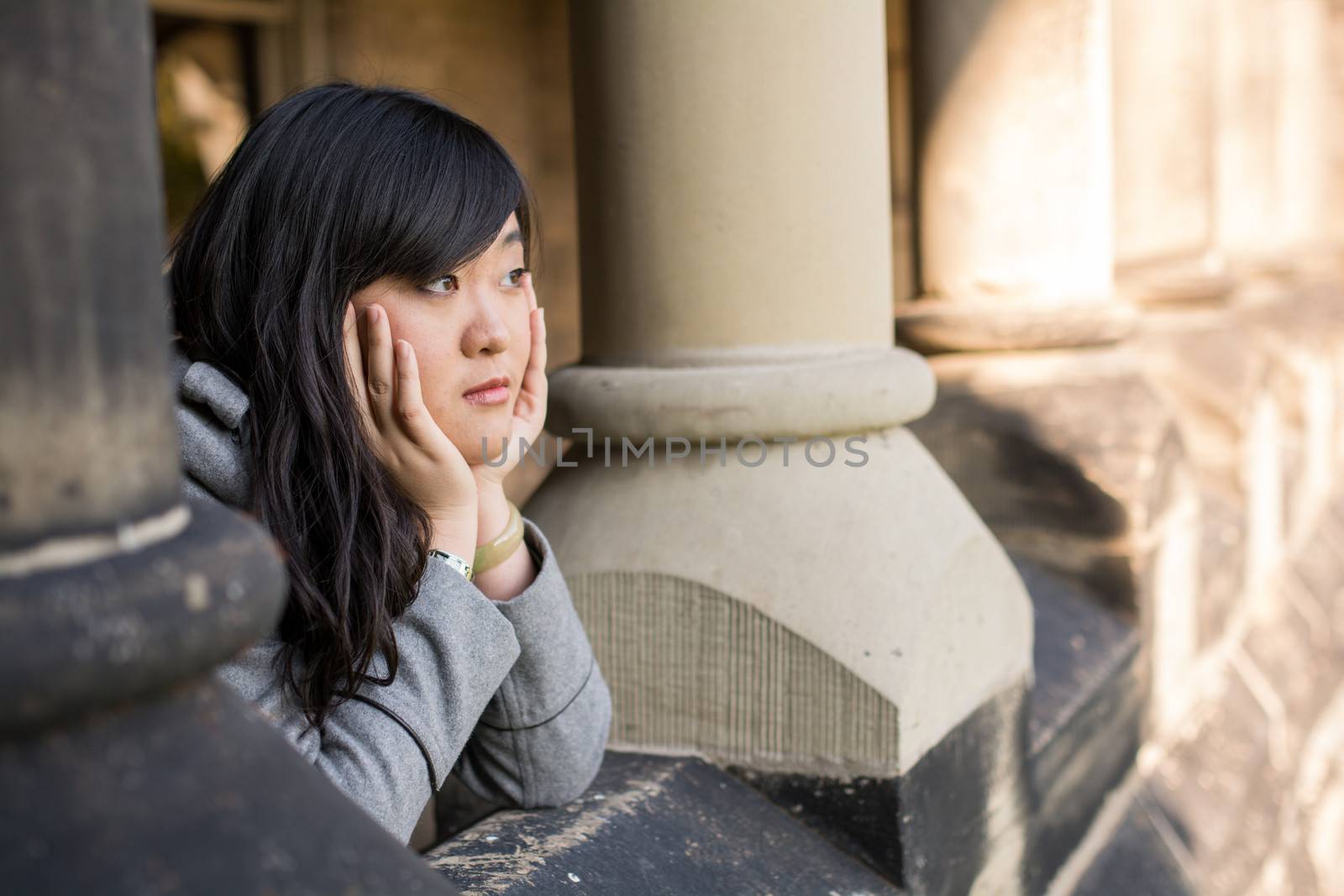 young woman leaning forward next to stone pillars