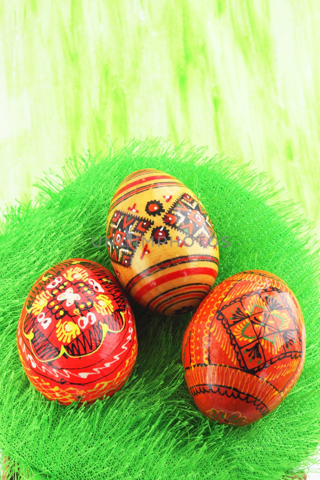 Three eggs with the manual painting against the green background