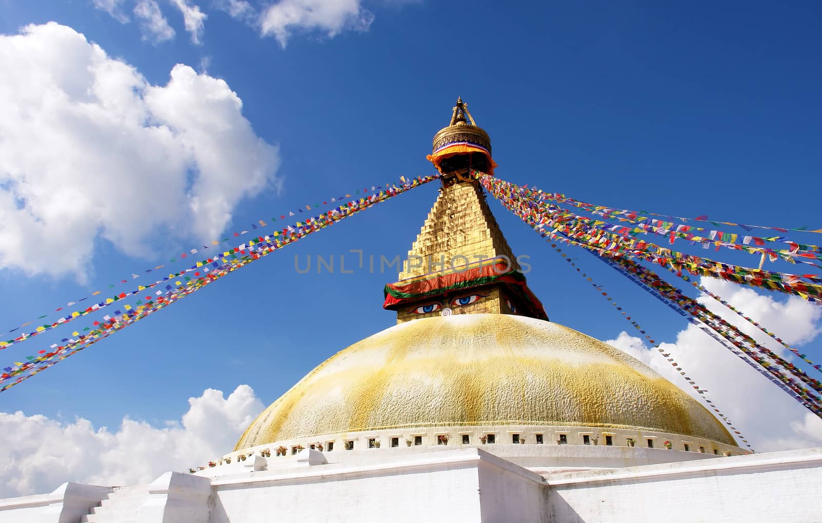 bodhnath stupa in kathmandu with buddha eyes and prayer flags on clear blue sky background