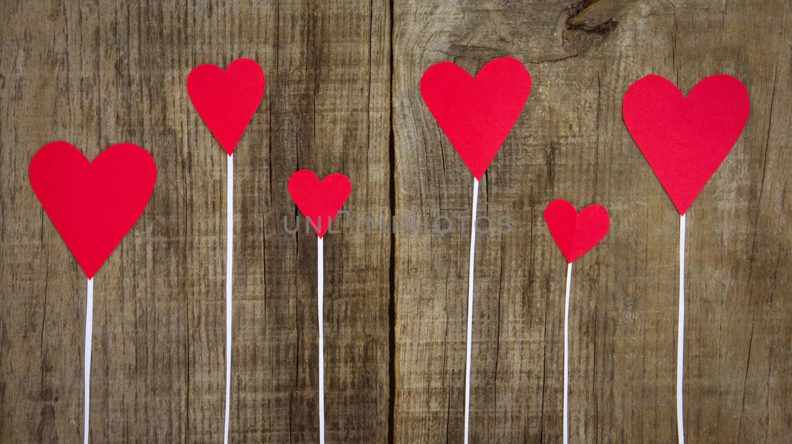 Several Red Hearts on wooden textured background.