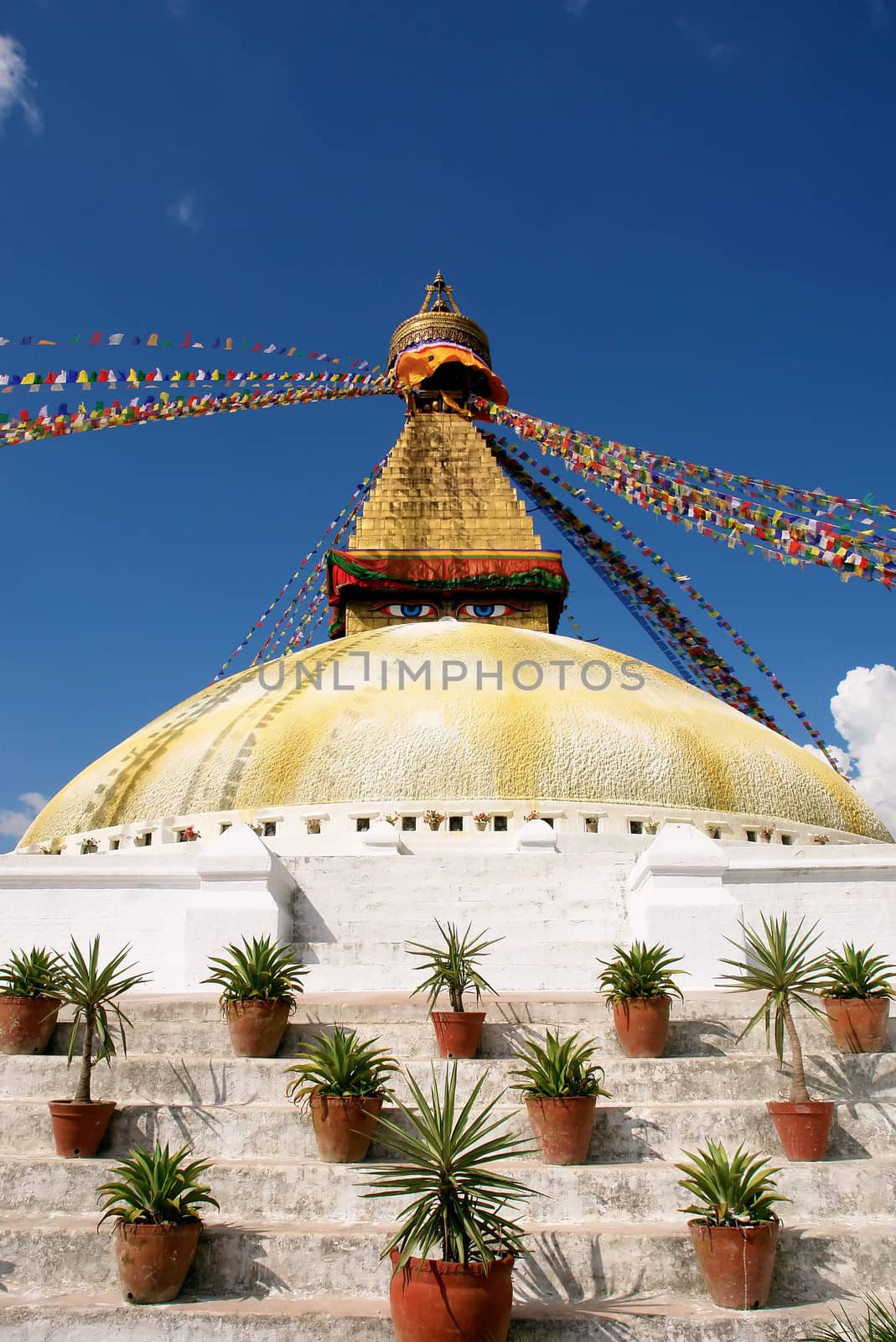 bodhnath stupa in kathmandu with buddha eyes and prayer flags on clear blue sky background