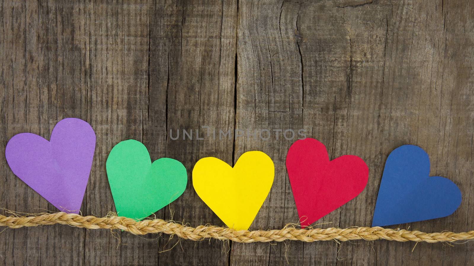Colorful paper hearts on wood textured background