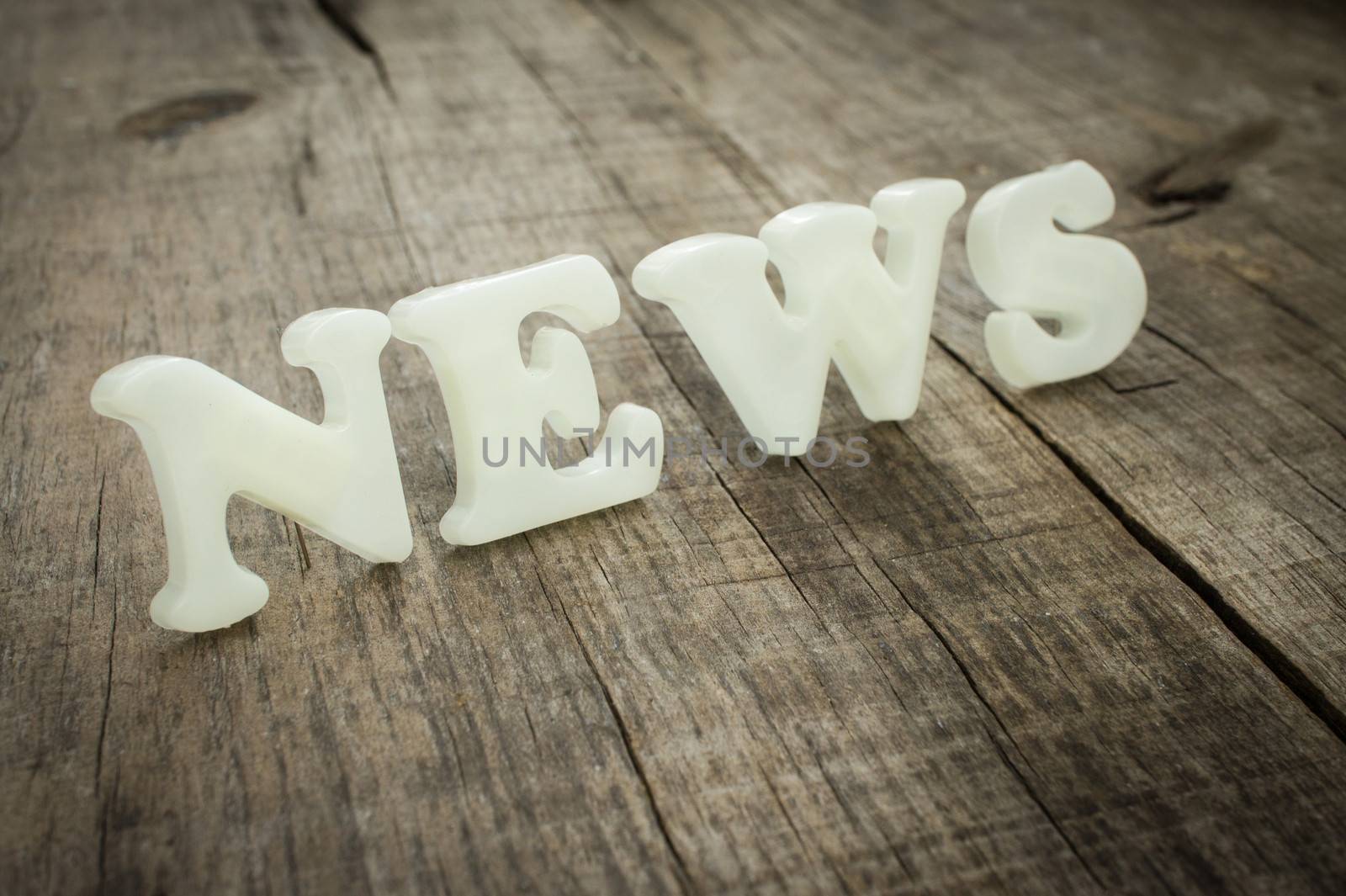 News out of plastic letters on wood background