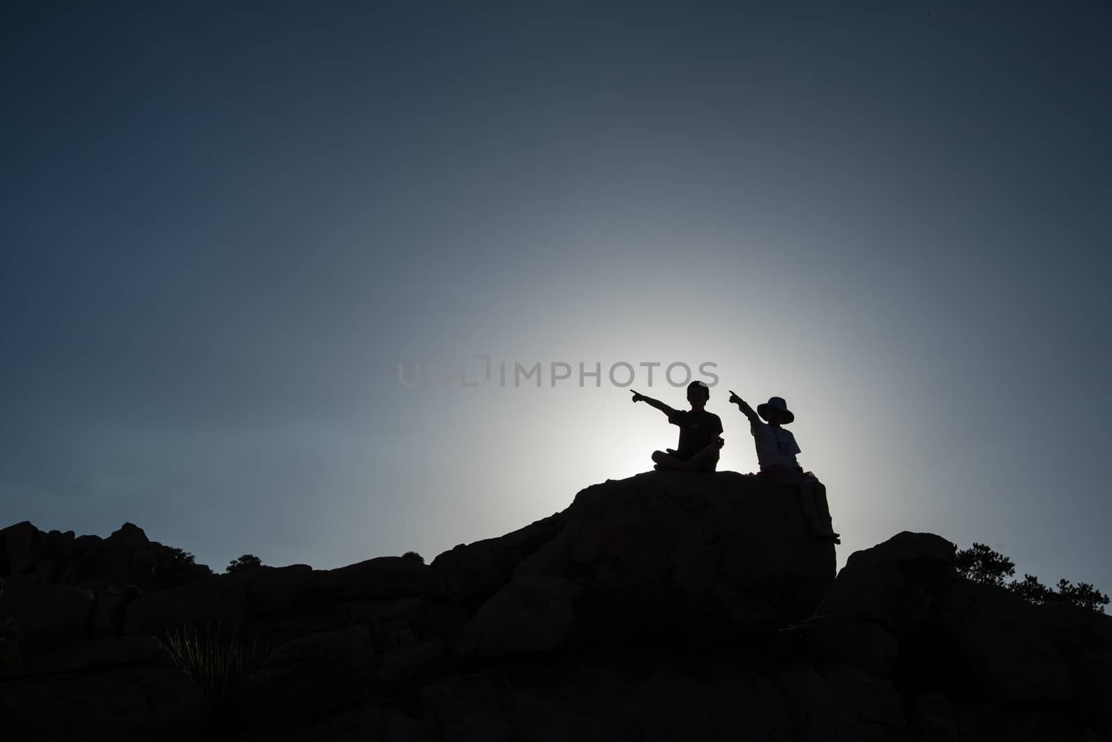 Two children pointing, sitting on rock by rongreer