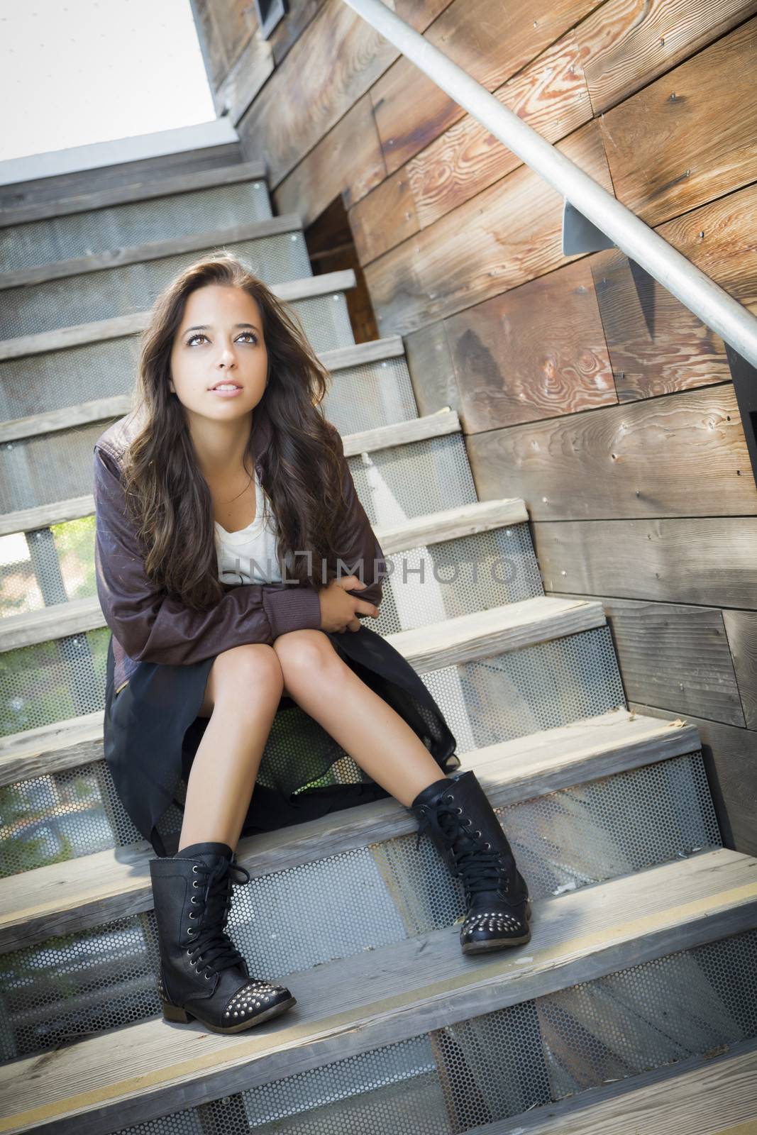 Portrait of a Pretty Mixed Race Young Adult Woman Sitting on a Staircase Wearing Leather Boots and Jacket.