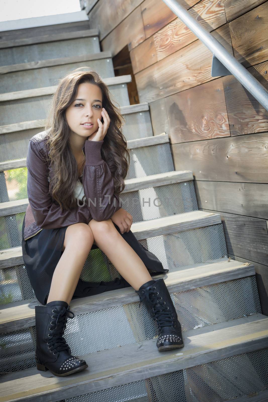 Portrait of a Pretty Mixed Race Young Adult Woman Sitting on a Staircase Wearing Leather Boots and Jacket.