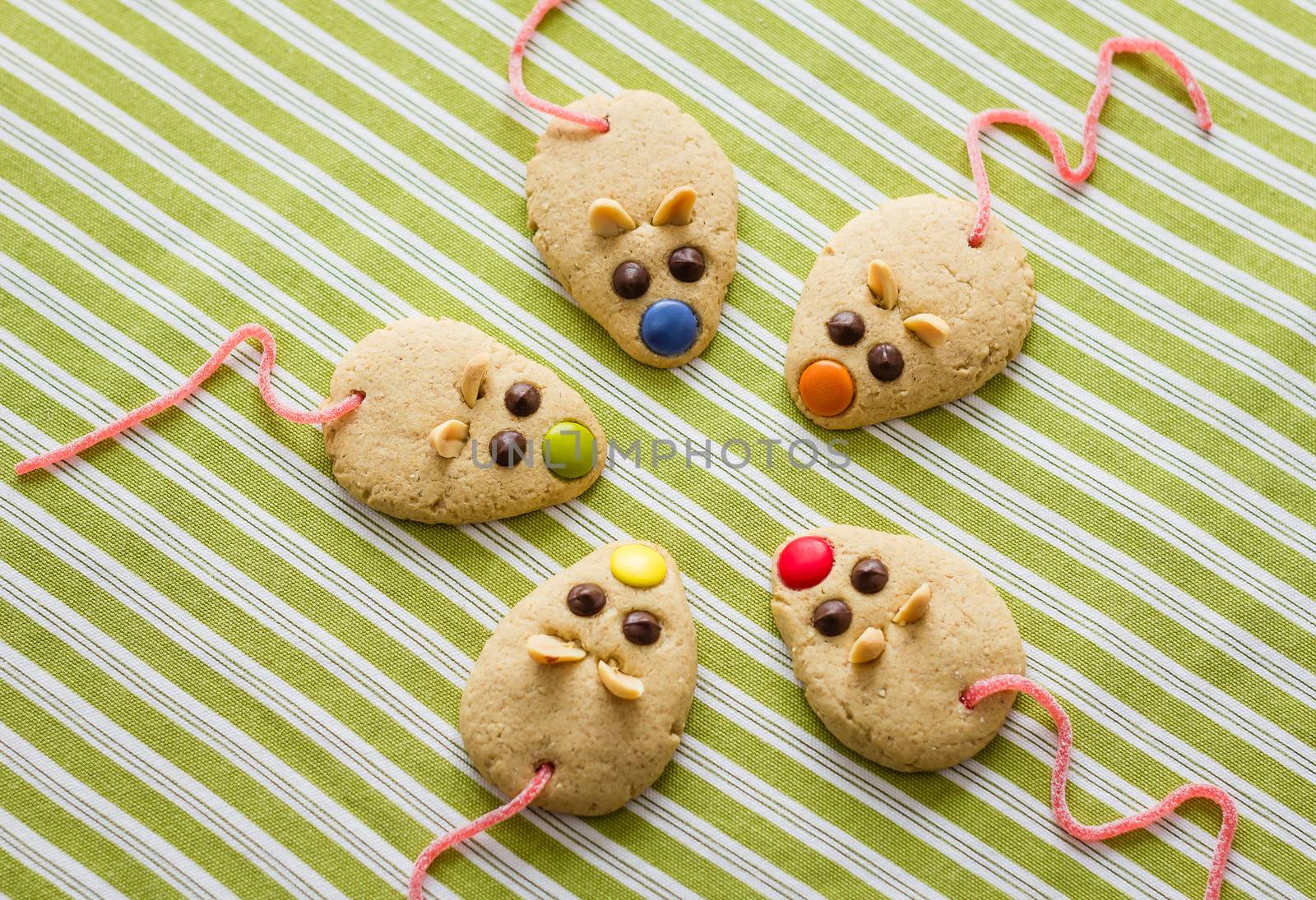 Cookies with mouse shaped and red licorice tail over green striped tablecloth