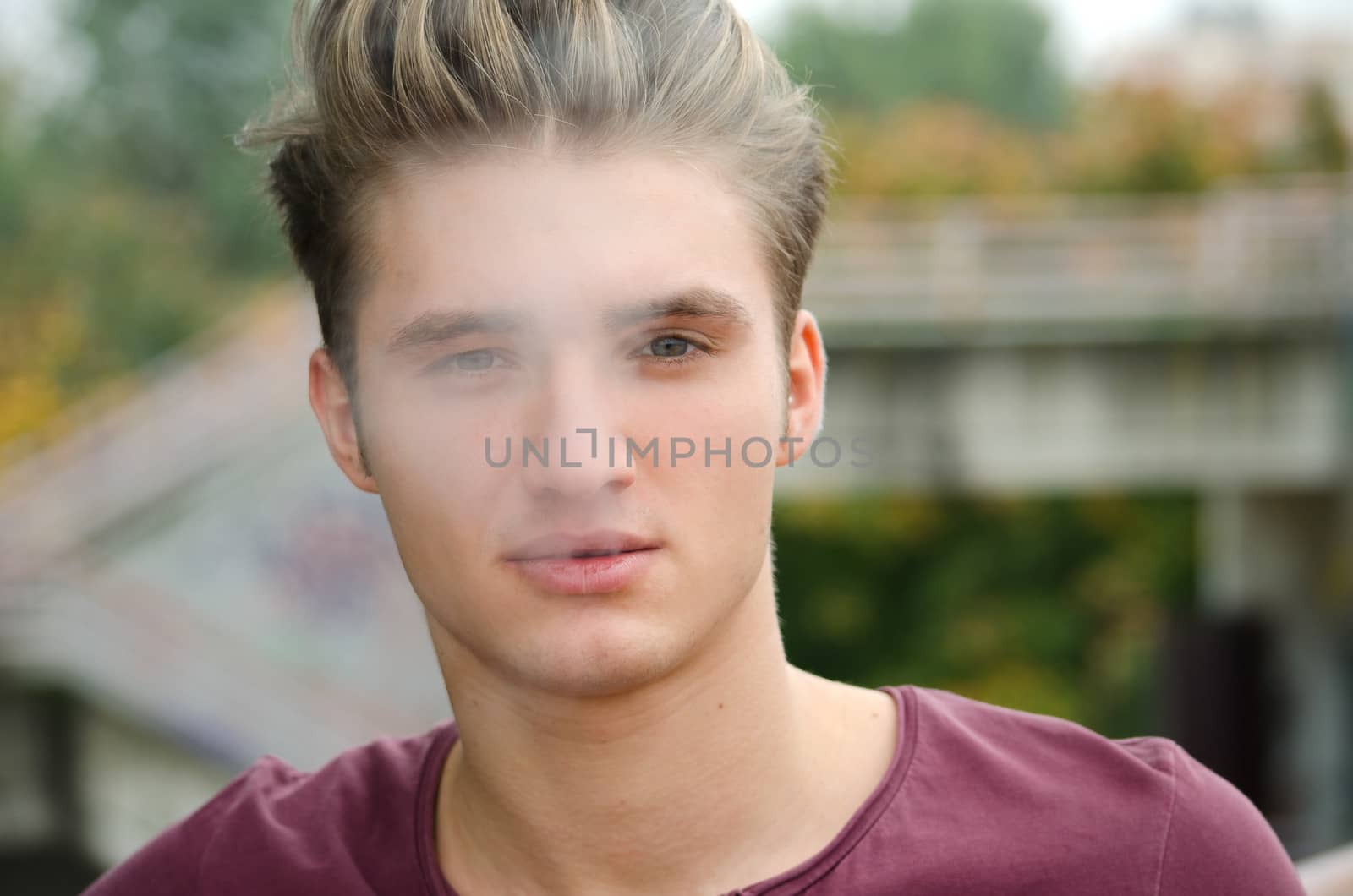 Handsome blond young man letting smoke out of his mouth, outdoors shot