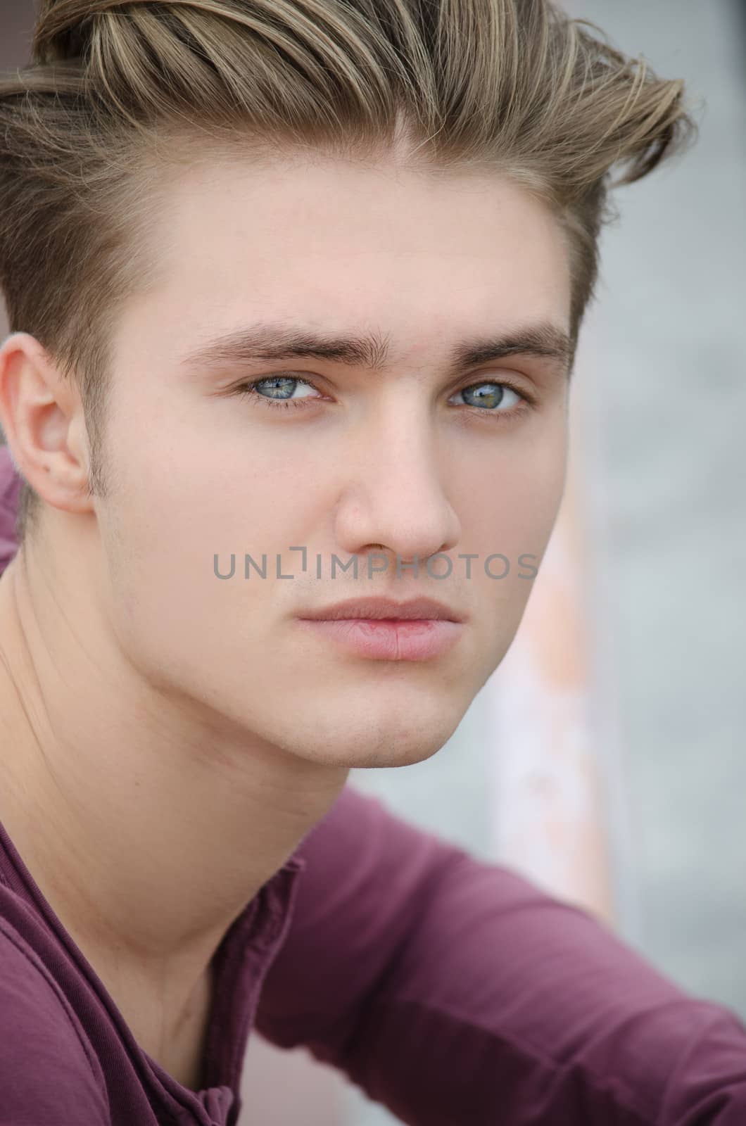Handsome blond young man head-shot outdoors, looking at camera