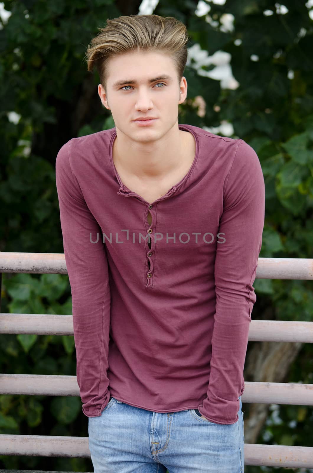 Handsome blond young man standing with hands in his jeans pockets, outdoors