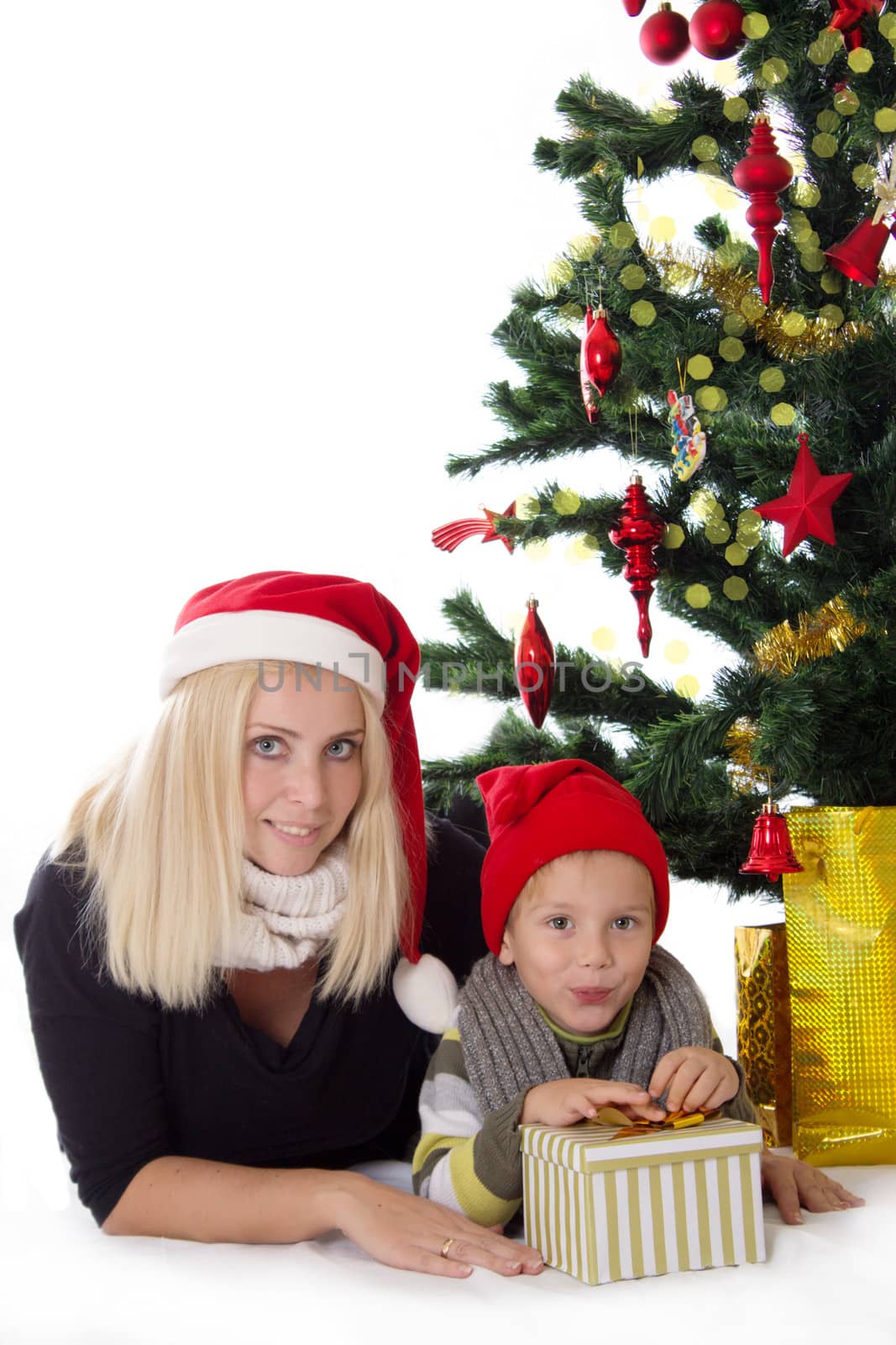 Happy mother and son lying under Christmas tree over white