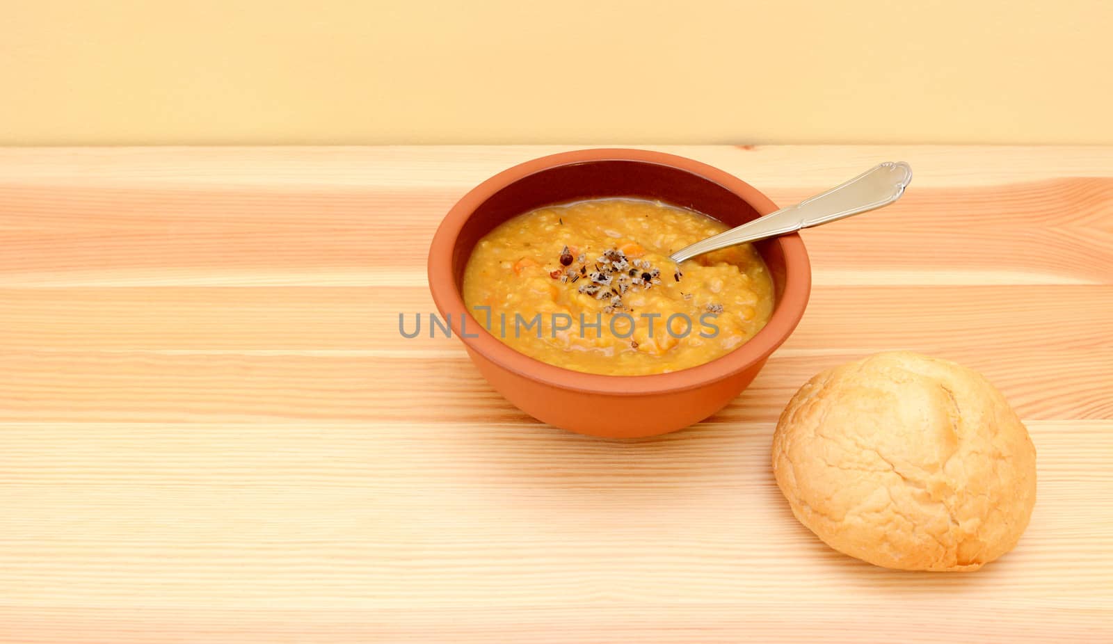 Seasoned lentil soup ready to eat with a crusty bread roll with copy space