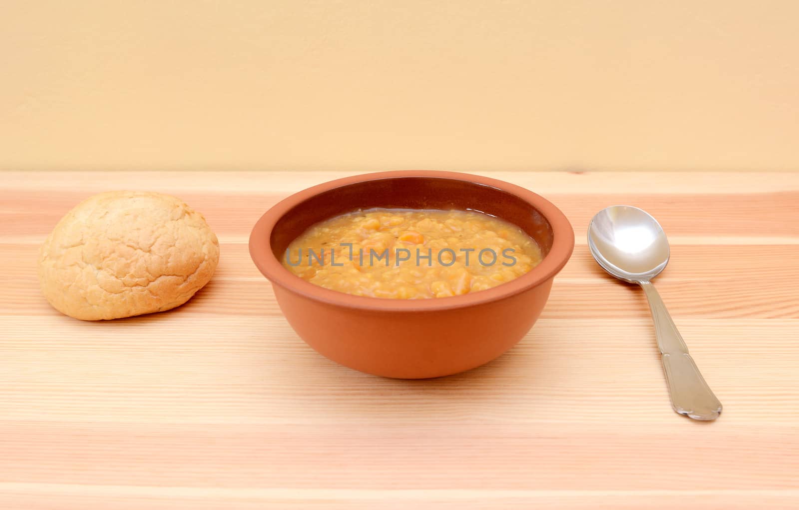 Hearty lentil soup served in a bowl with a crusty bread roll