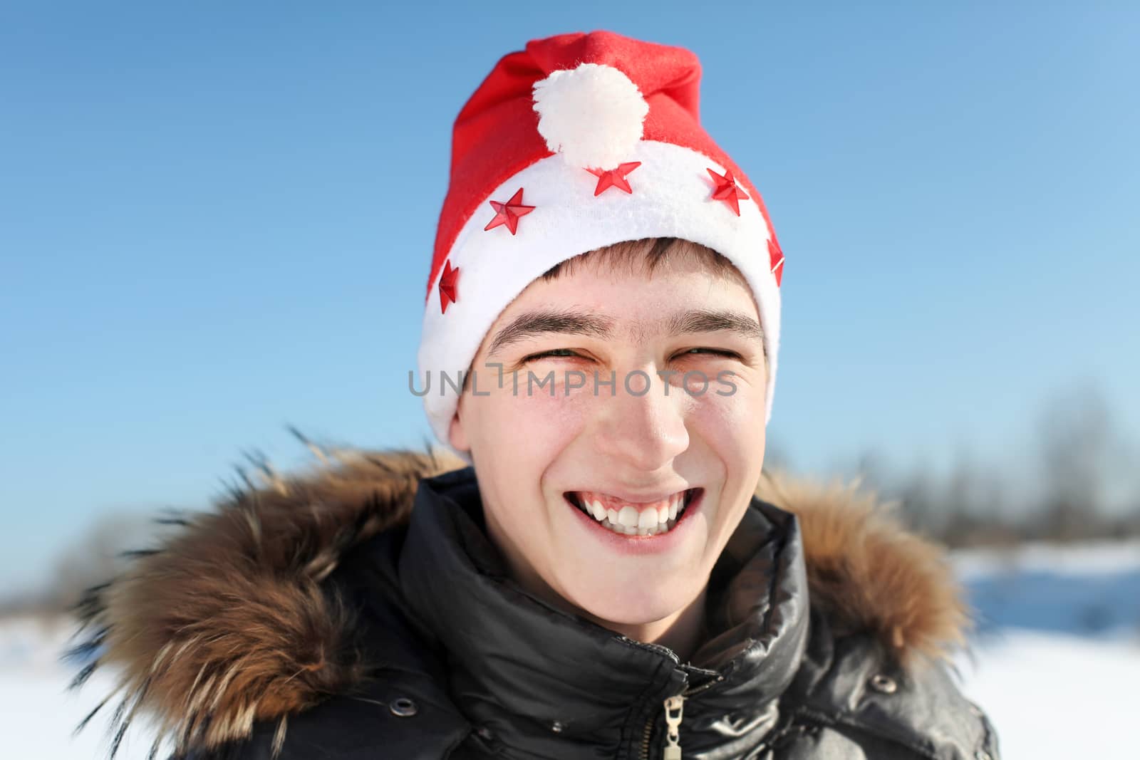 Portrait of Happy Young Man in Santa's hat outdoor in the winter