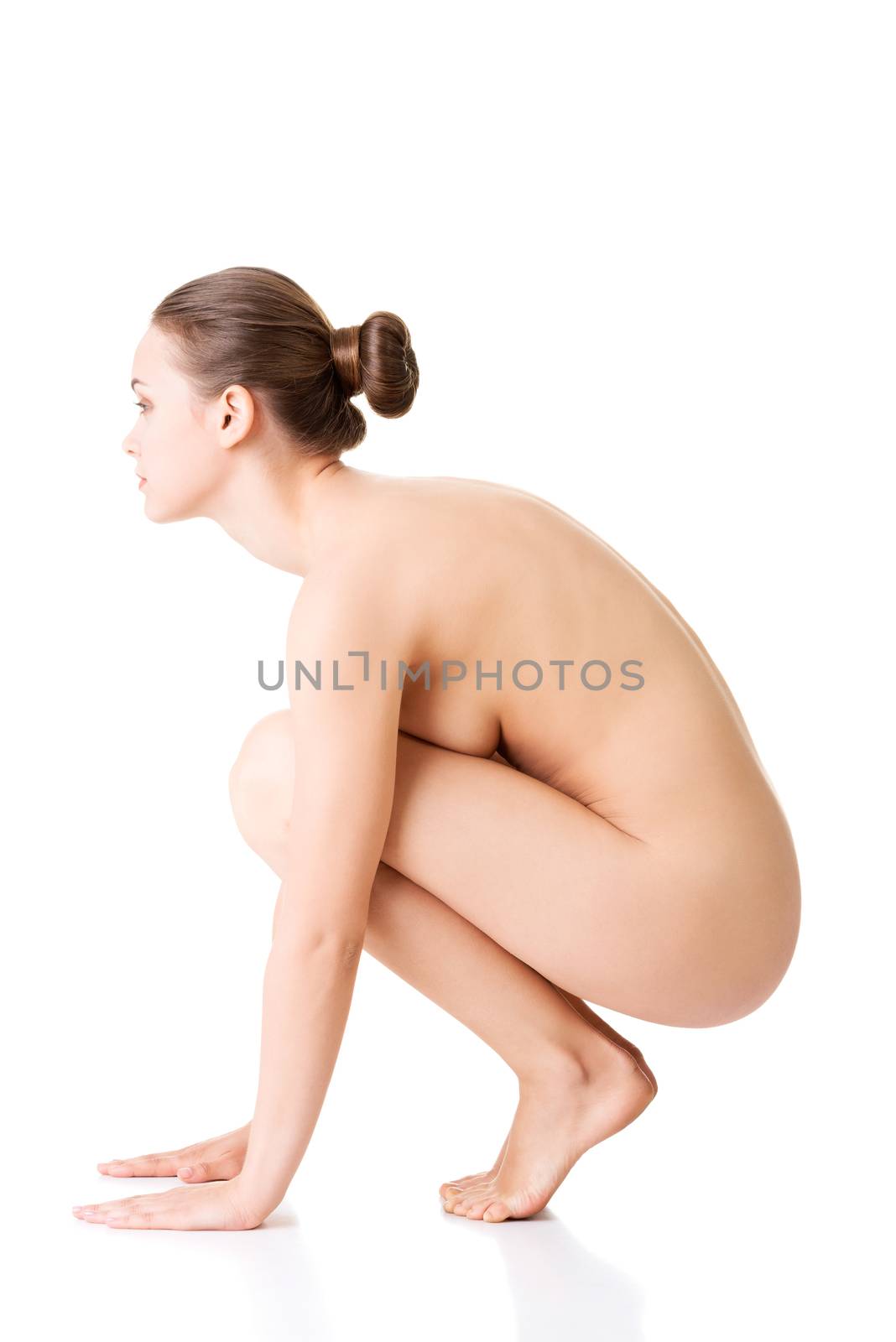Attractive young naked woman in a crouch. Side view.isolated on white.