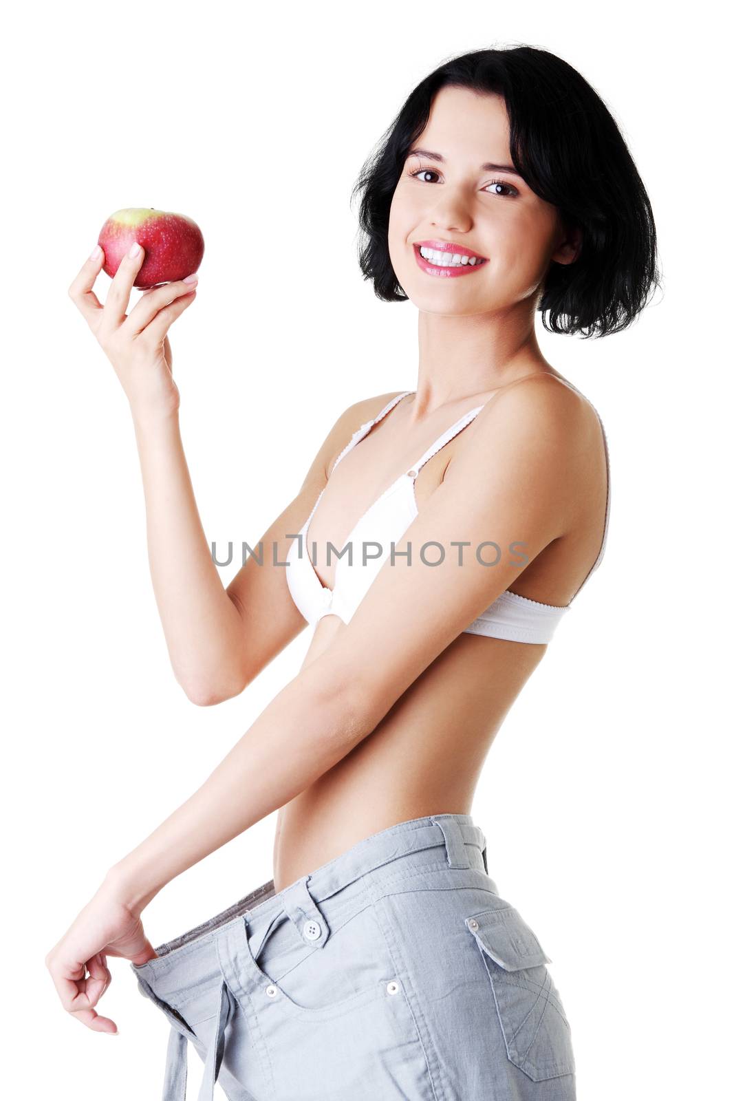 Attractive woman in baggy trousers with apple. Isolated on white.