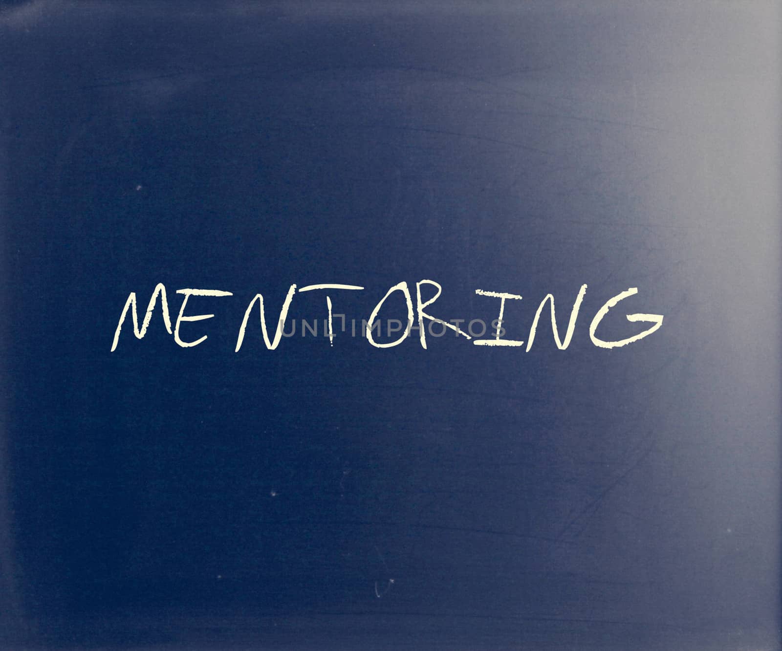 The word "Mentoring" handwritten with white chalk on a blackboard.