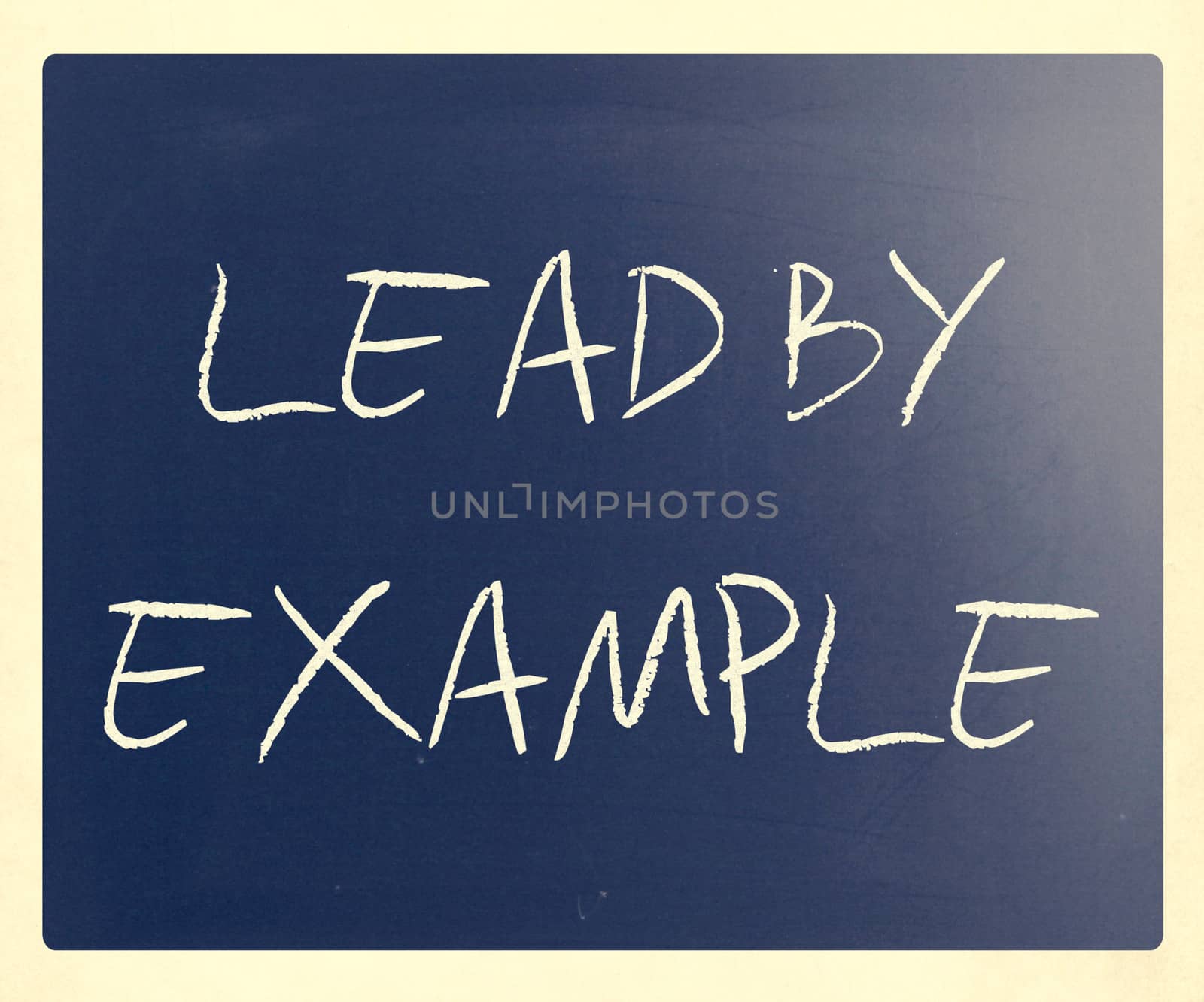 "Lead by example" handwritten with white chalk on a blackboard.