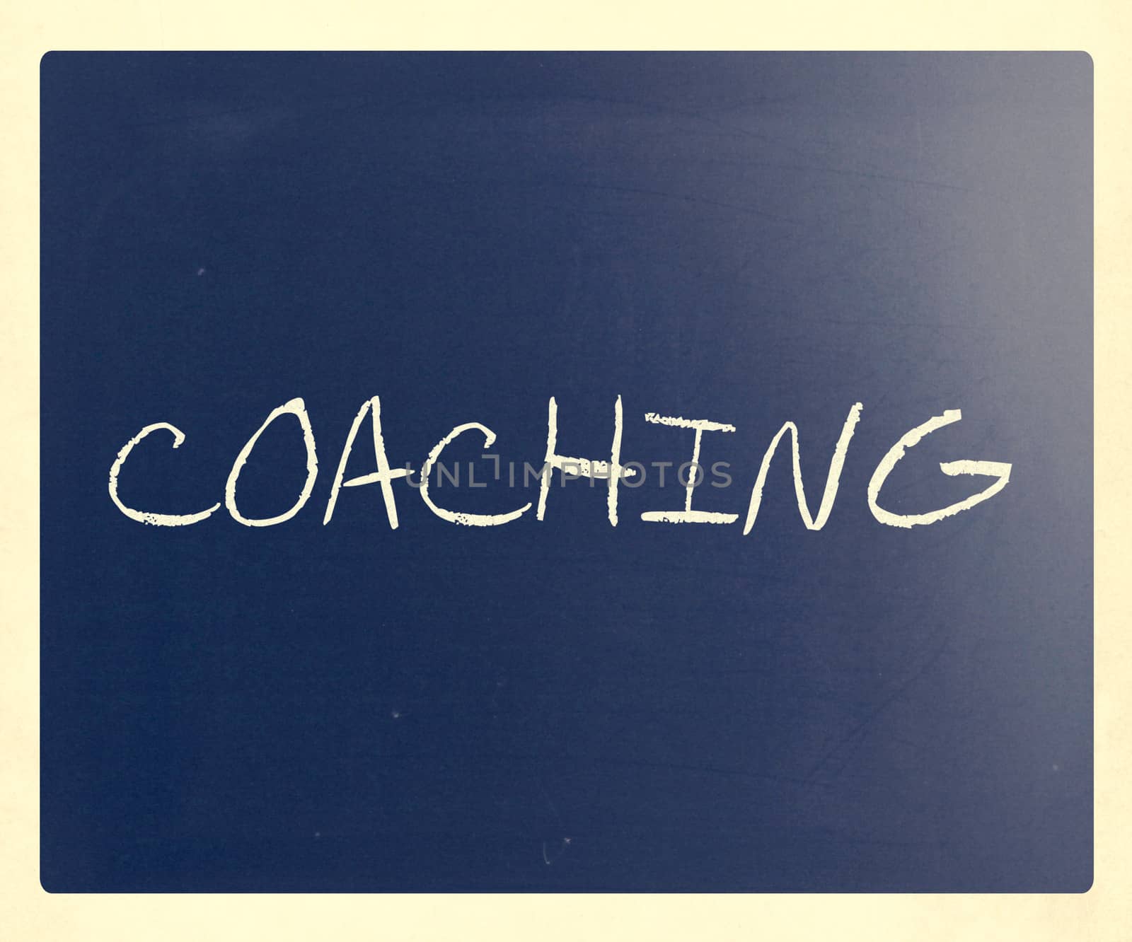 "Coaching" handwritten with white chalk on a blackboard.