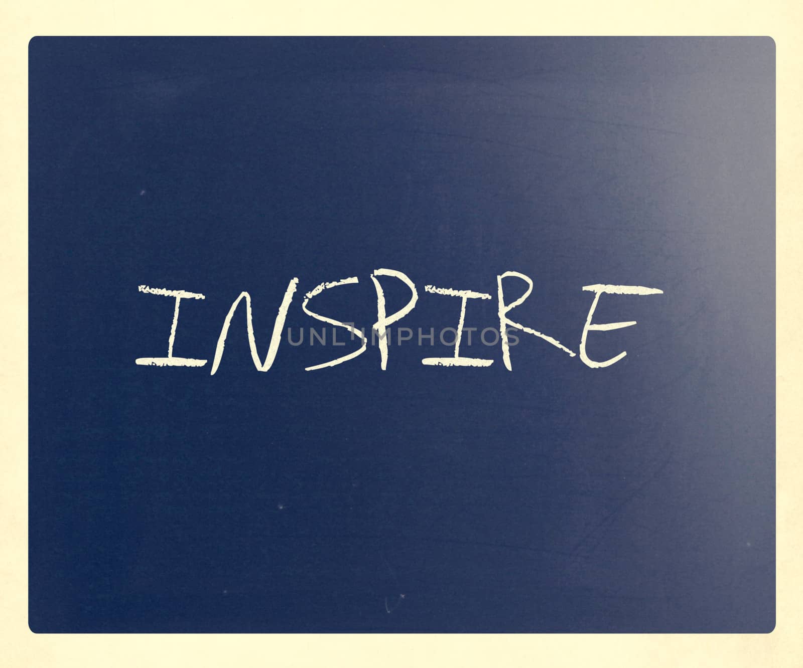 "Inspire" handwritten with white chalk on a blackboard.