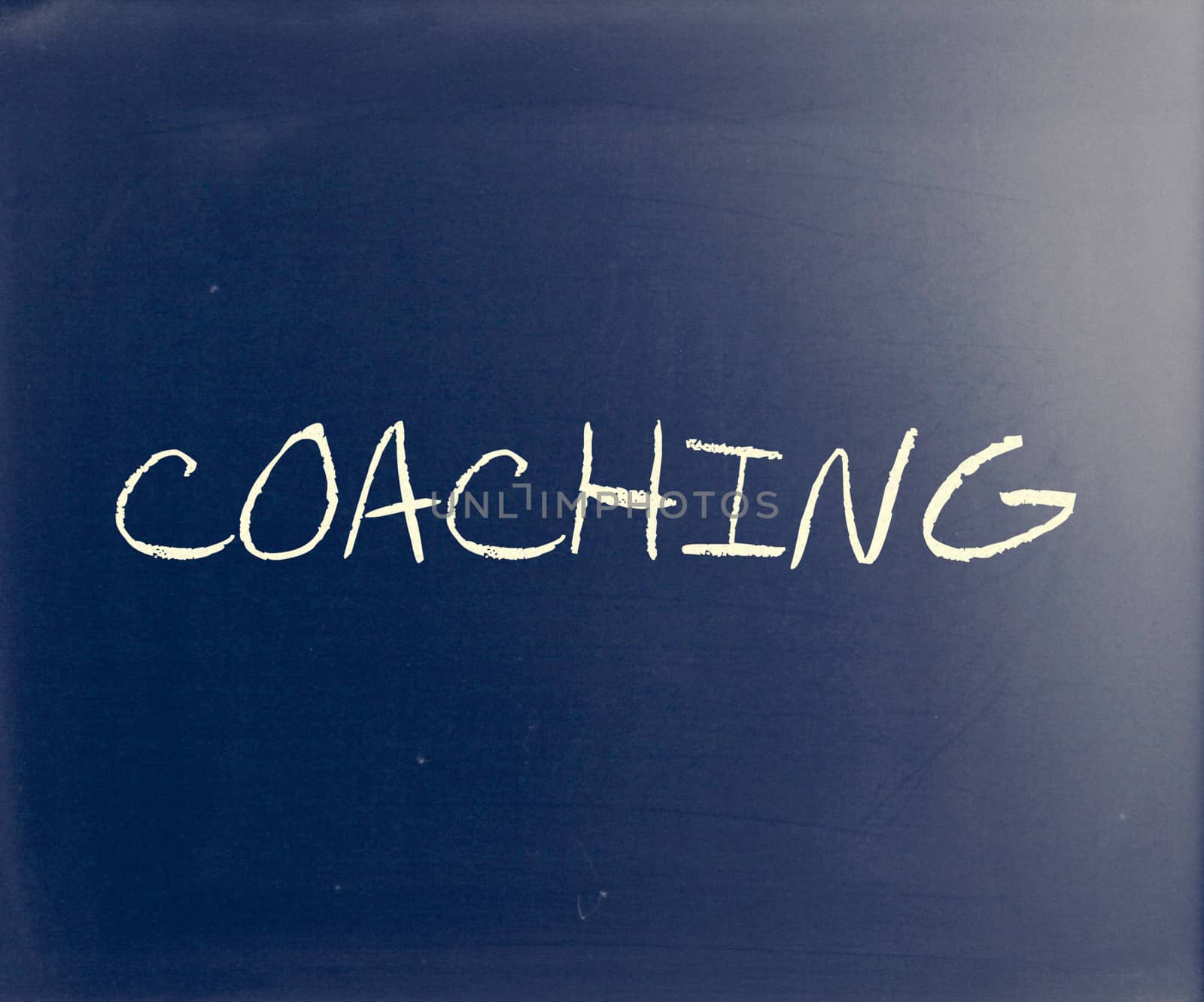 "Coaching" handwritten with white chalk on a blackboard.