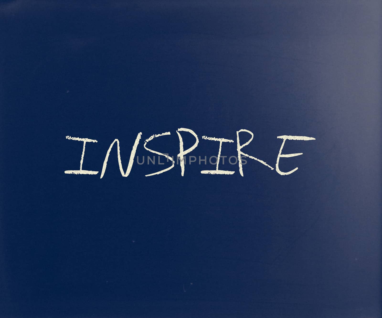 "Inspire" handwritten with white chalk on a blackboard.