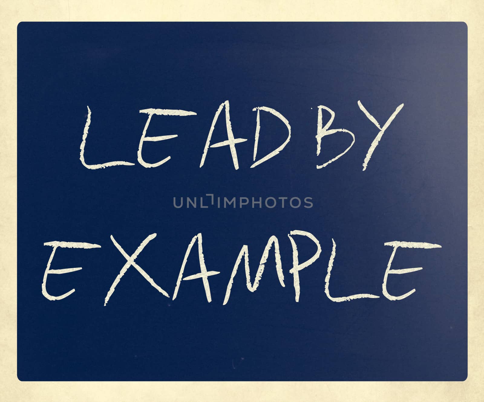 "Lead by example" handwritten with white chalk on a blackboard.